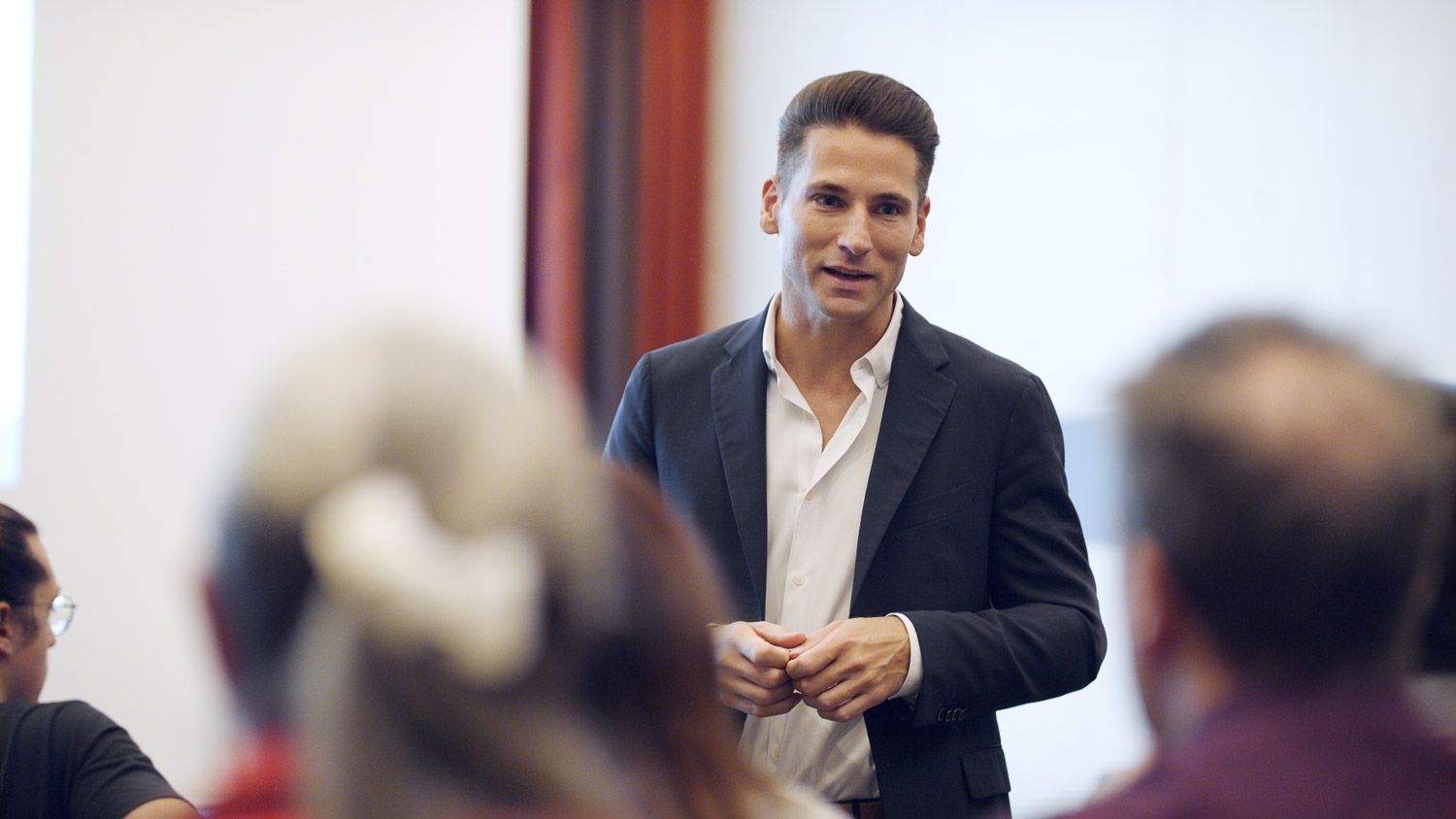 Redner im Sakko spricht vor einem kleinen Publikum bei einem Vortrag im Eventfilm