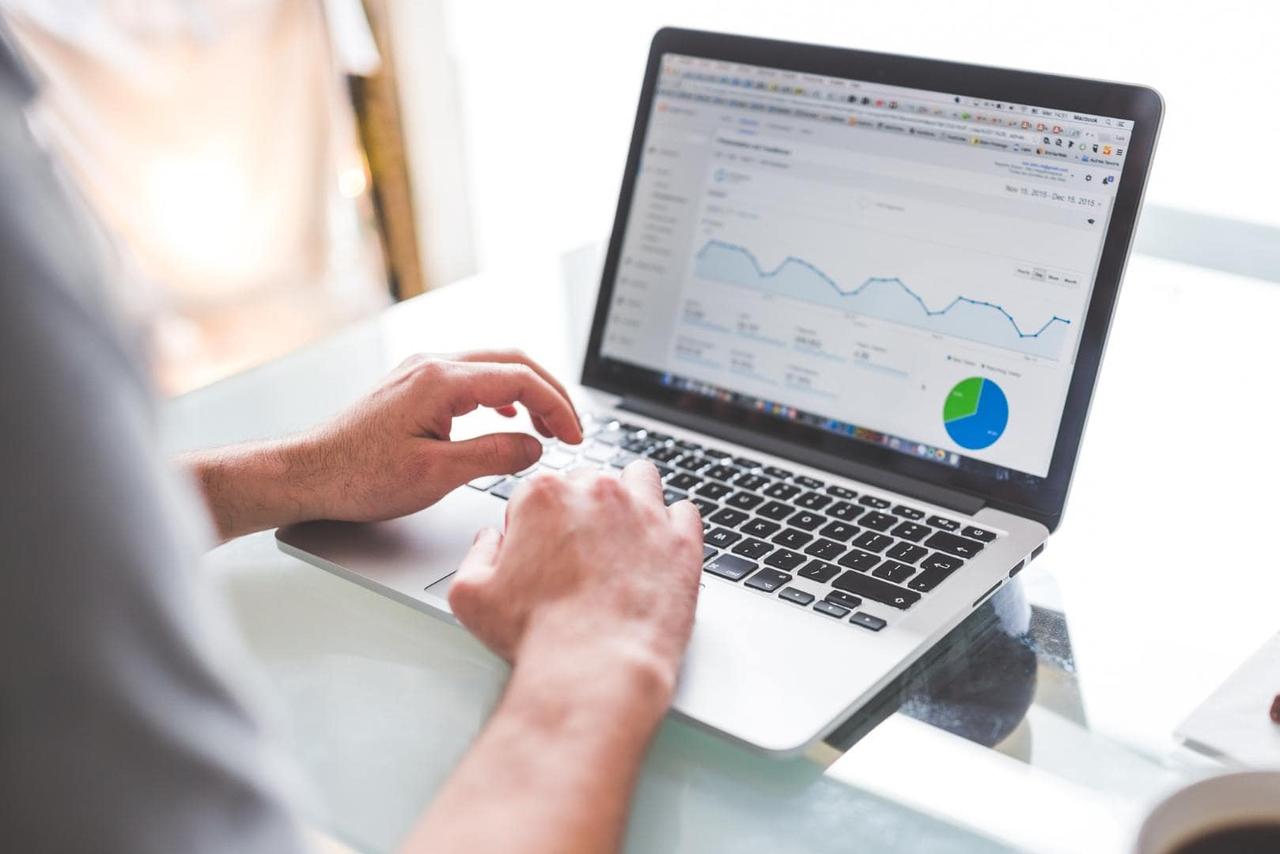 Hände tippen am Laptop mit Analytics-Diagrammen – Erfolgsmessung einer Videomarketing-Kampagne