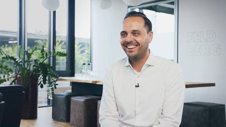 Lächelnder Interviewpartner mit Ansteckmikrofon in einem hellen Büro während eines Imagevideo-Drehs