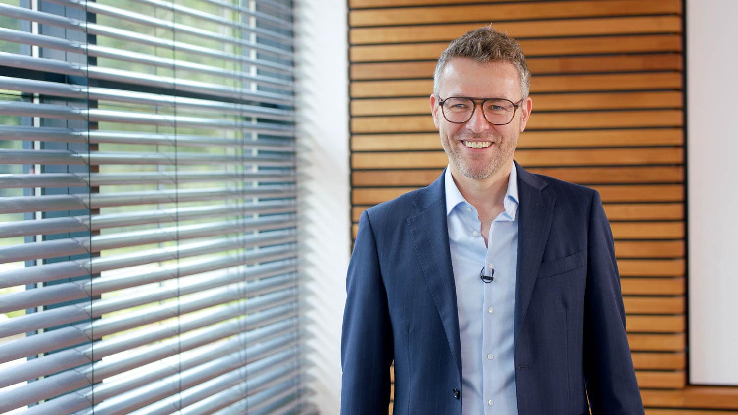 Lächelnder Interviewpartner mit Brille im Anzug bei der Kleusberg-Expertenrunde im Eventfilm