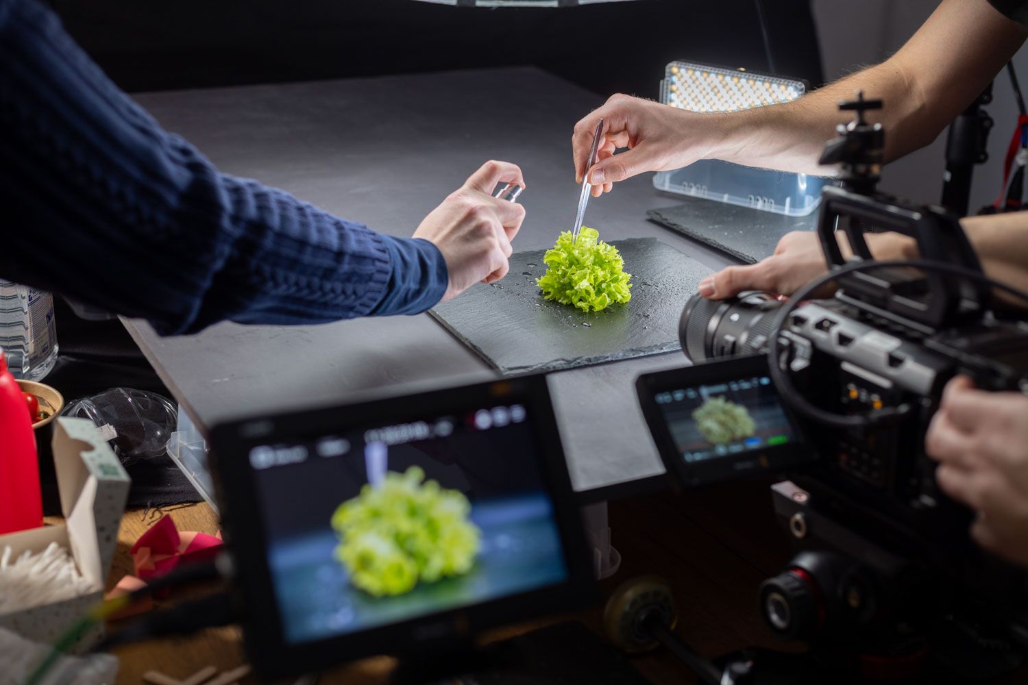 Produktfilm-Dreh im Studio: Hände richten ein Produkt vor der Kamera an, Monitore zeigen das Livebild