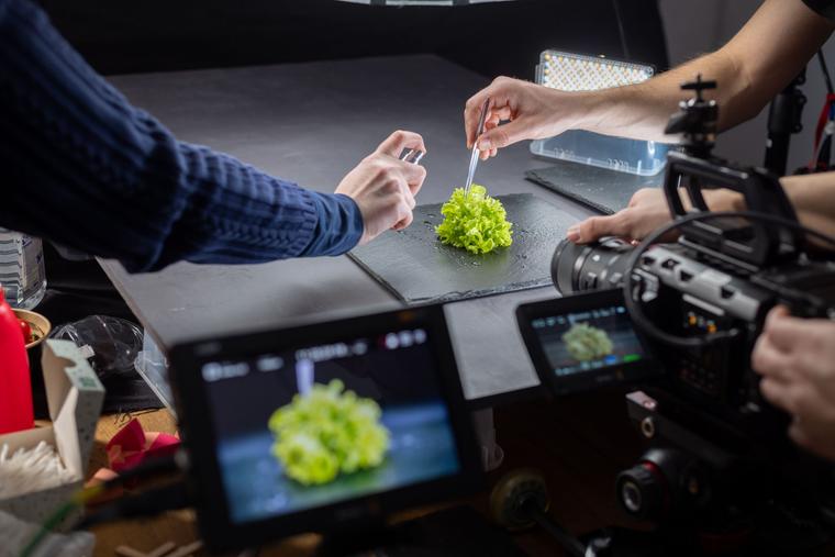 Produktfilm-Dreh im Studio: Hände richten ein Produkt vor der Kamera an, Monitore zeigen das Livebild