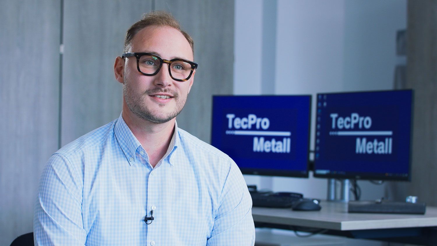 Interviewpartner mit Brille erzählt vor TecPro-Metall-Monitoren seine Geschichte in der Video-Case-Study