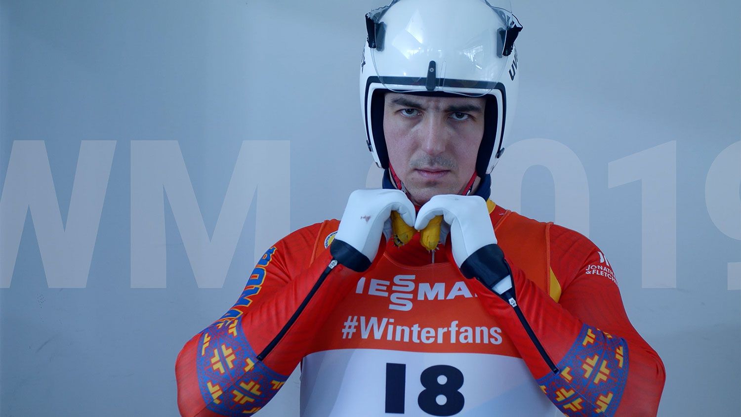 Konzentrierter Rennrodler mit Helm schließt seinen Rennanzug bei der Rodel-WM 2019 im Eventfilm