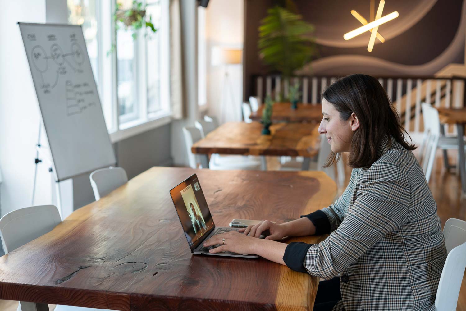 Eine Frau führt einen Videoanruf auf ihrem Laptop in einem modernen Büro einer Filmagentur.