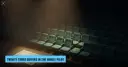 An empty auditorium where a handful of seats hold a single brass coin each, beside a blank certificate