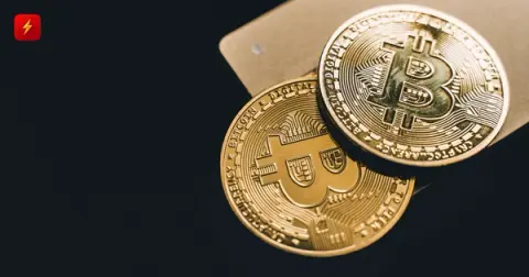 Gold bitcoin-branded coins resting on a payment card