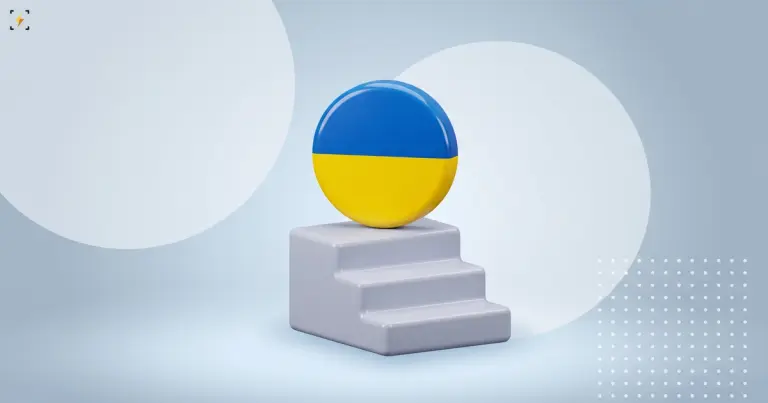 A glossy round badge with a blue and yellow two-stripe flag resting on the top step of a short three-step staircase on a light background