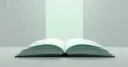 A matte charcoal book lying open under a soft mint light, illustrating a crypto glossary of 65 terms