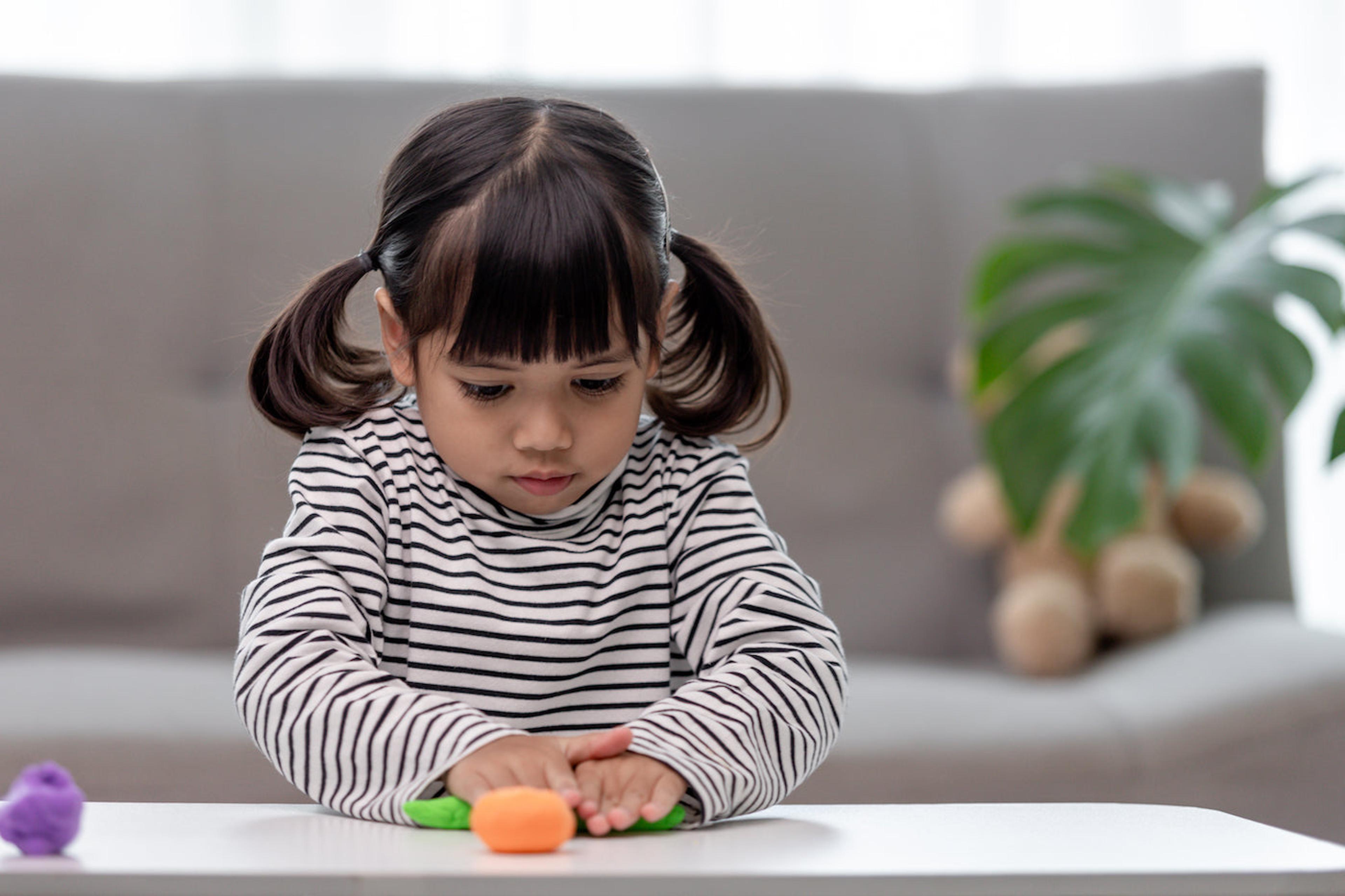 A toddler girl plays with playdough