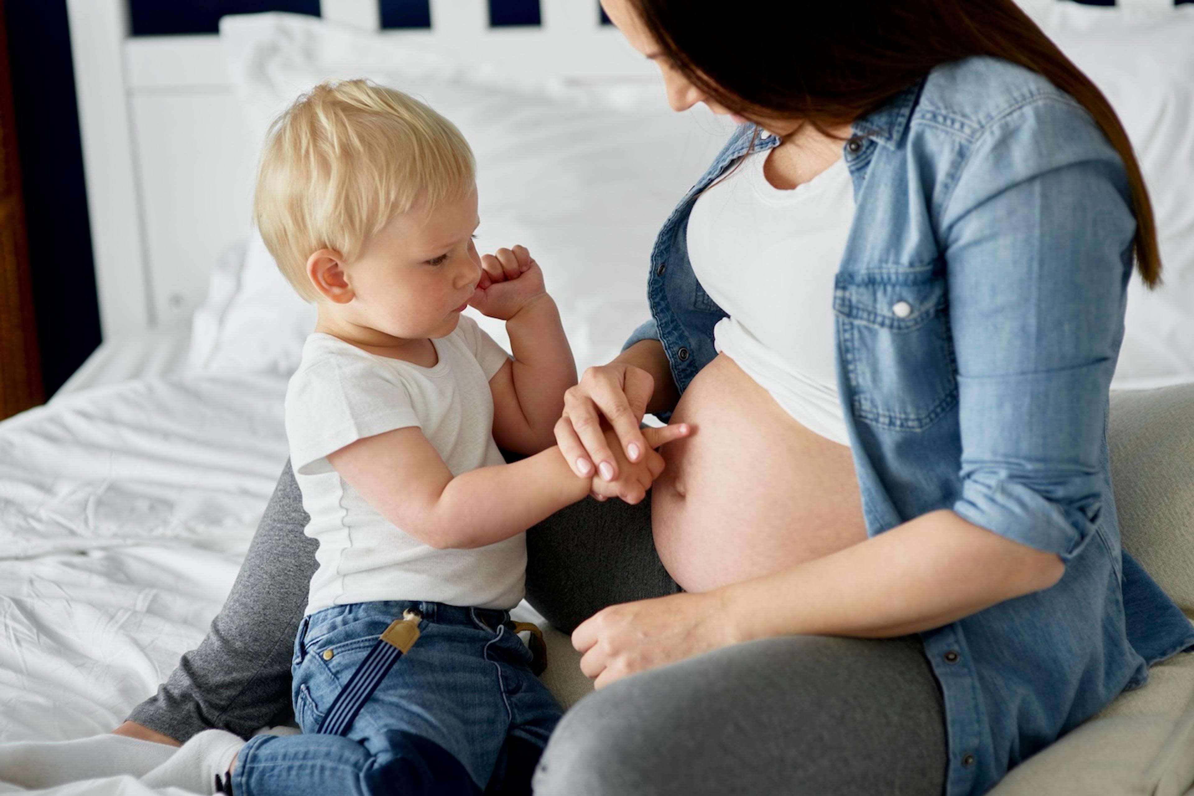 Toddler pointing at mum's pregnant belly