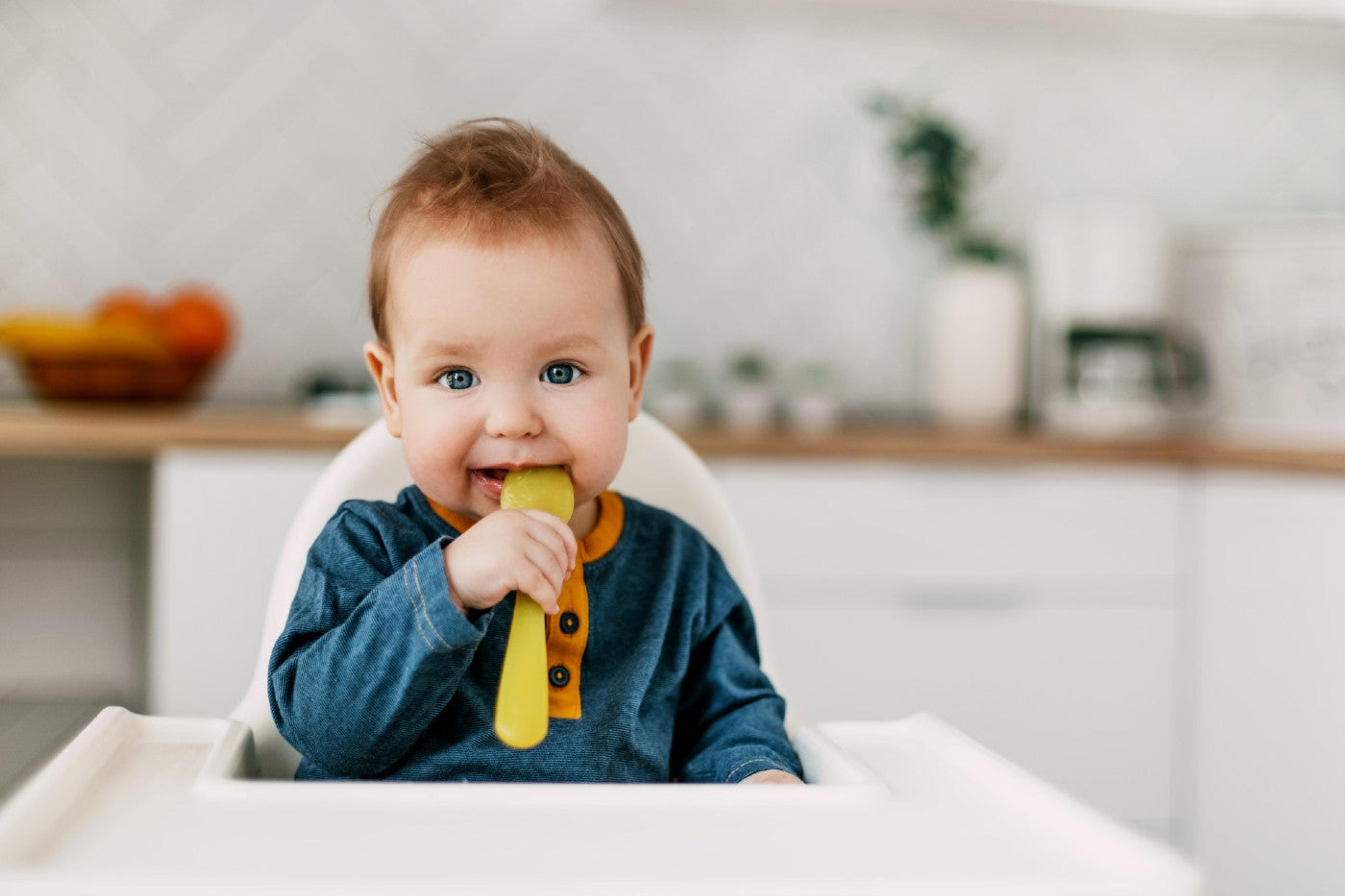 Baby chewing on silicone spoon in a high chair