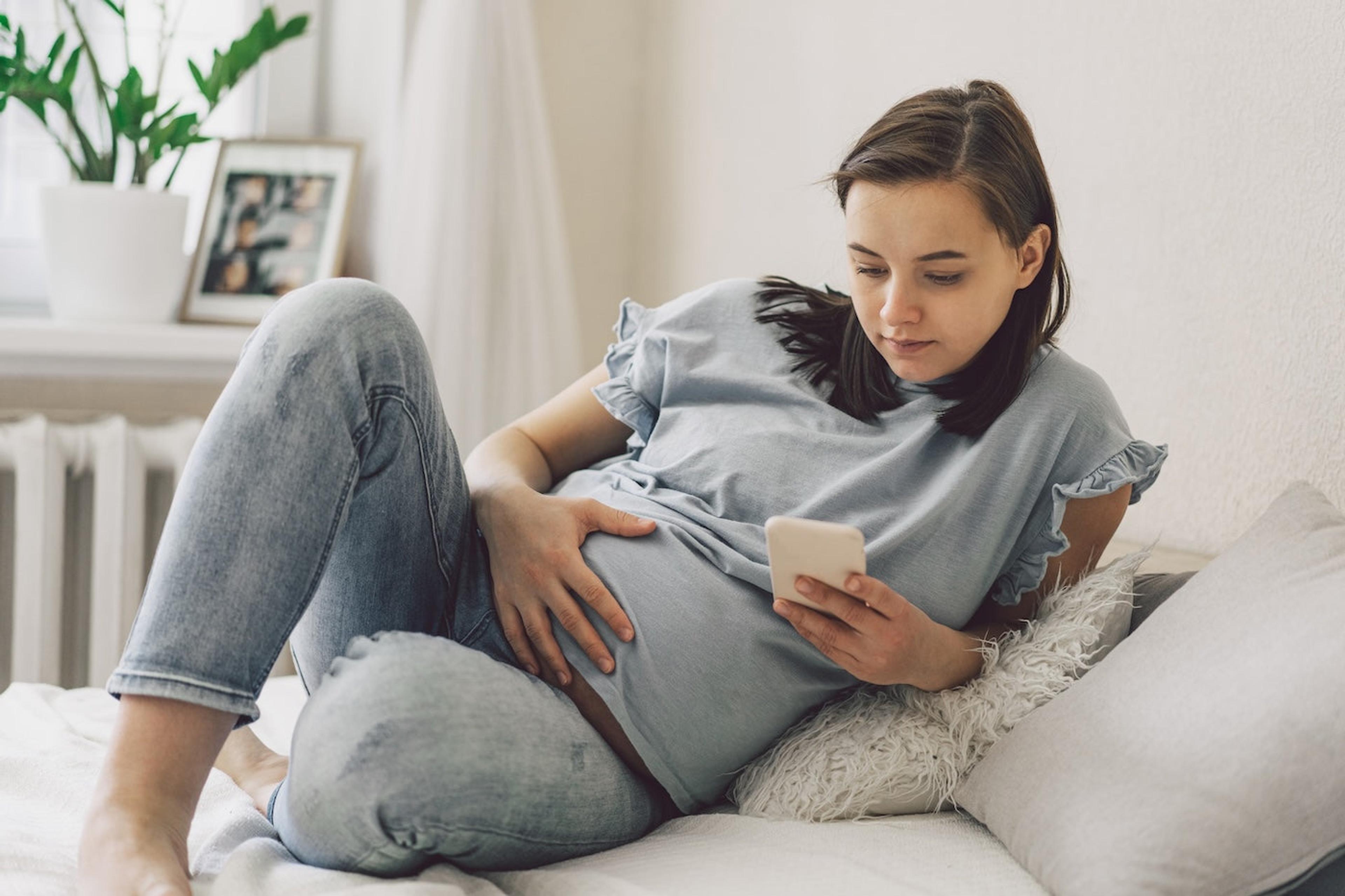 Worried pregnant woman looks at her phone