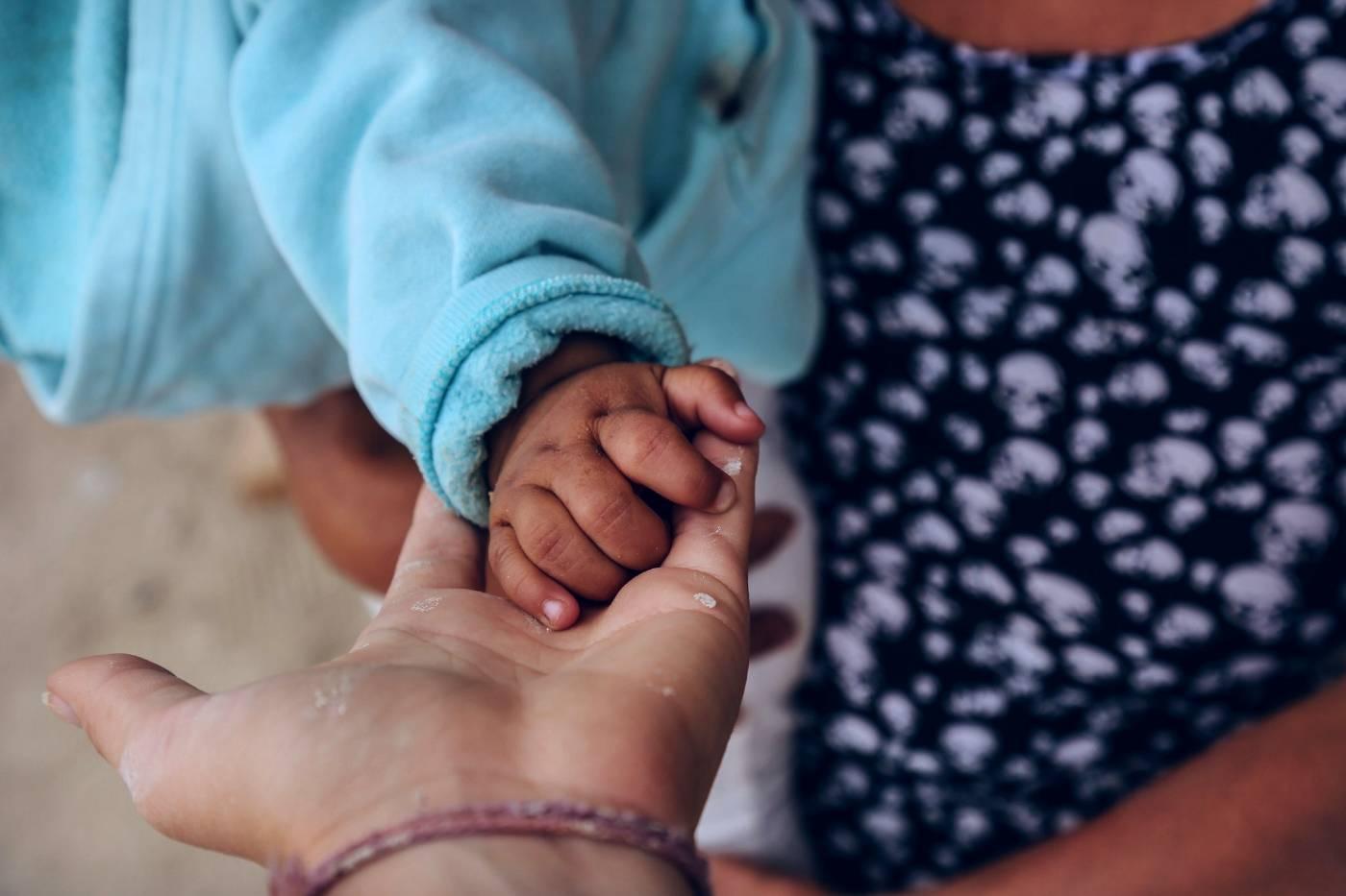 A woman's hand holding a baby's hand