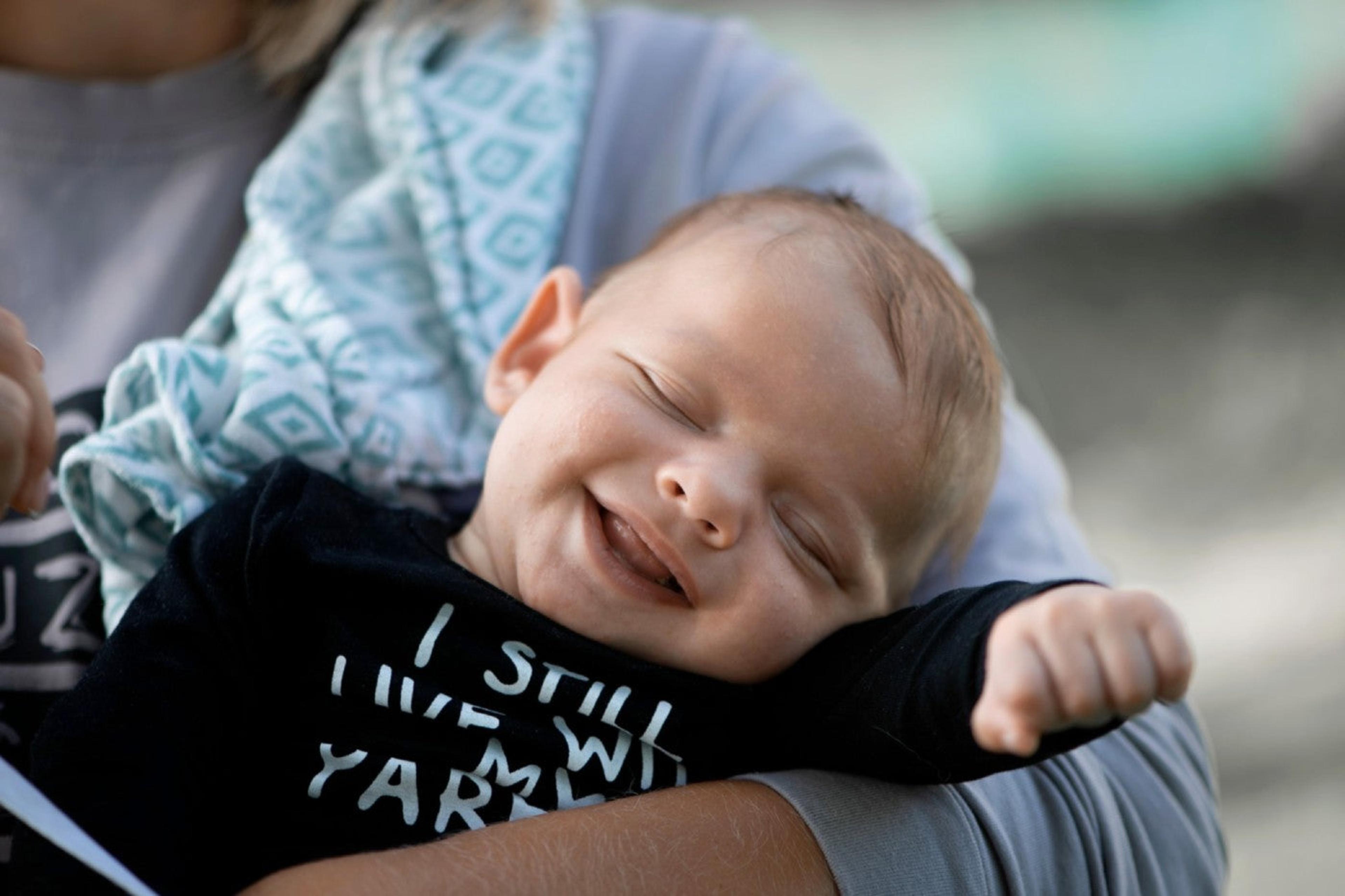 Smiling 6-week-old baby in caregiver's arms