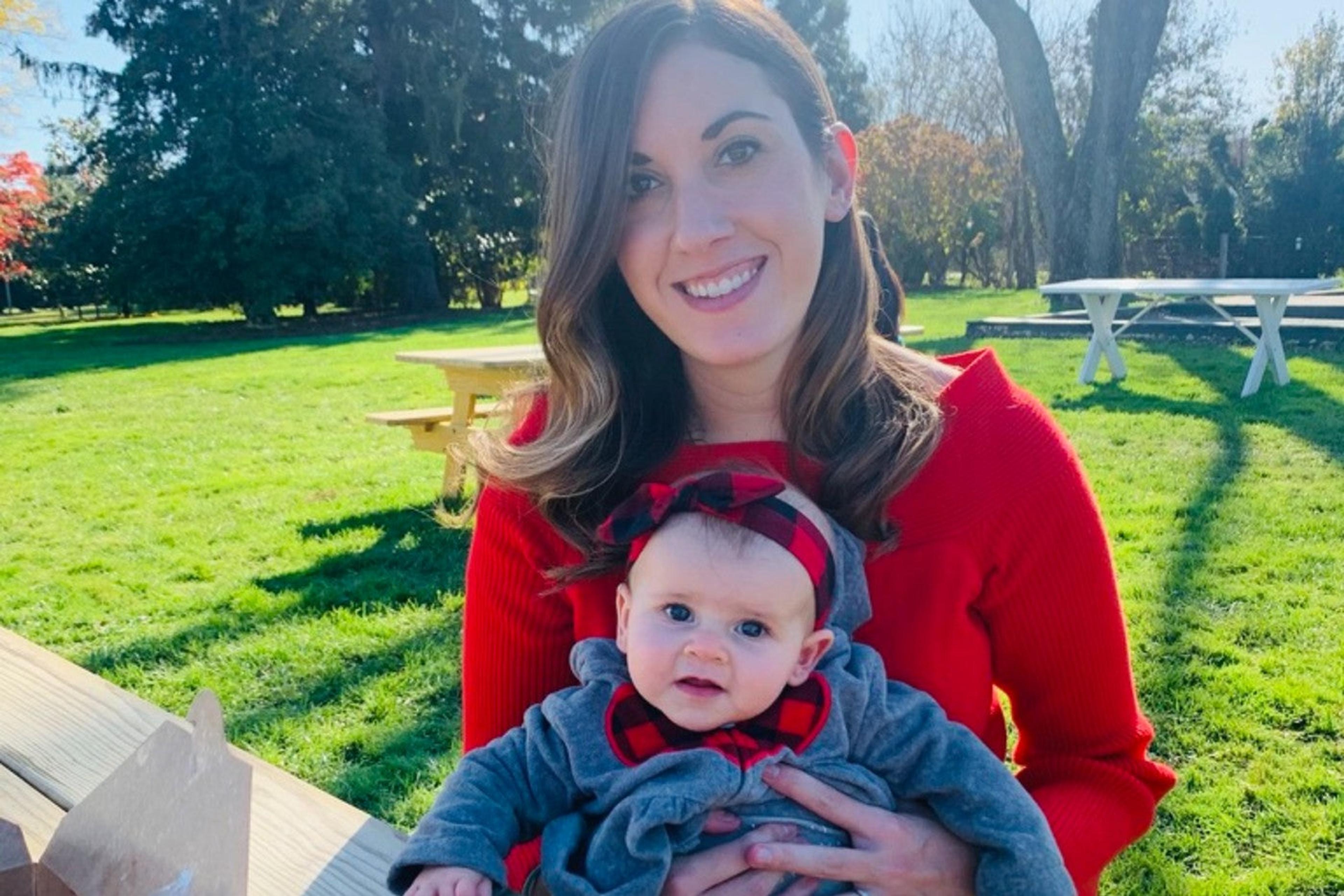 Mom holding baby girl at a park.