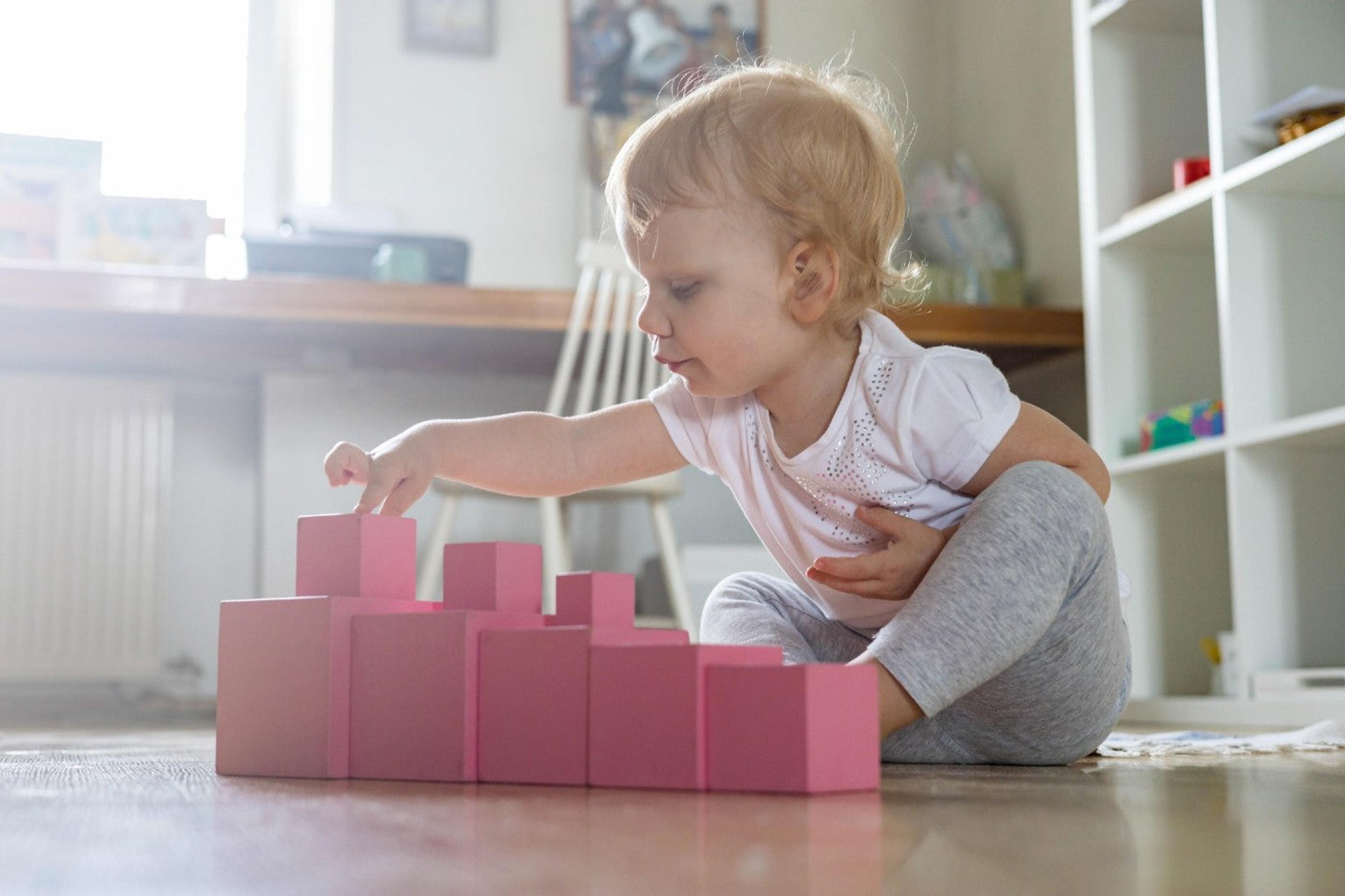 Toddler plays with pink graded Montessori blocks