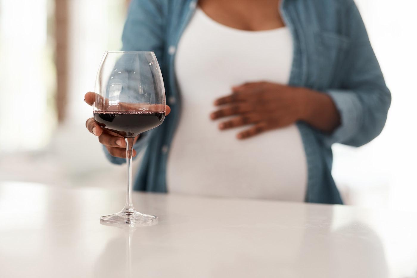 A woman holds a glass of wine during pregnancy
