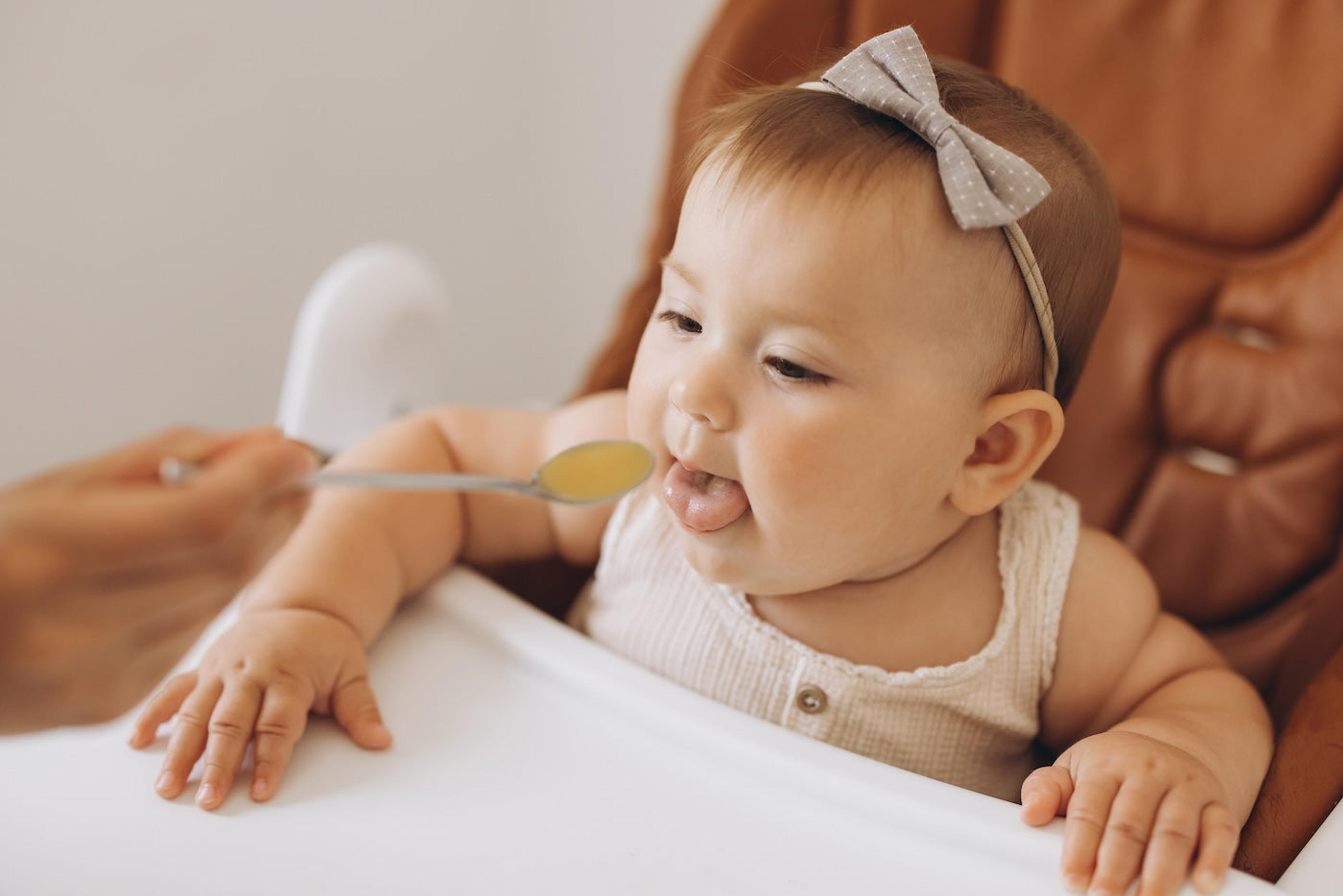 A baby eats a bite of food off a spoon