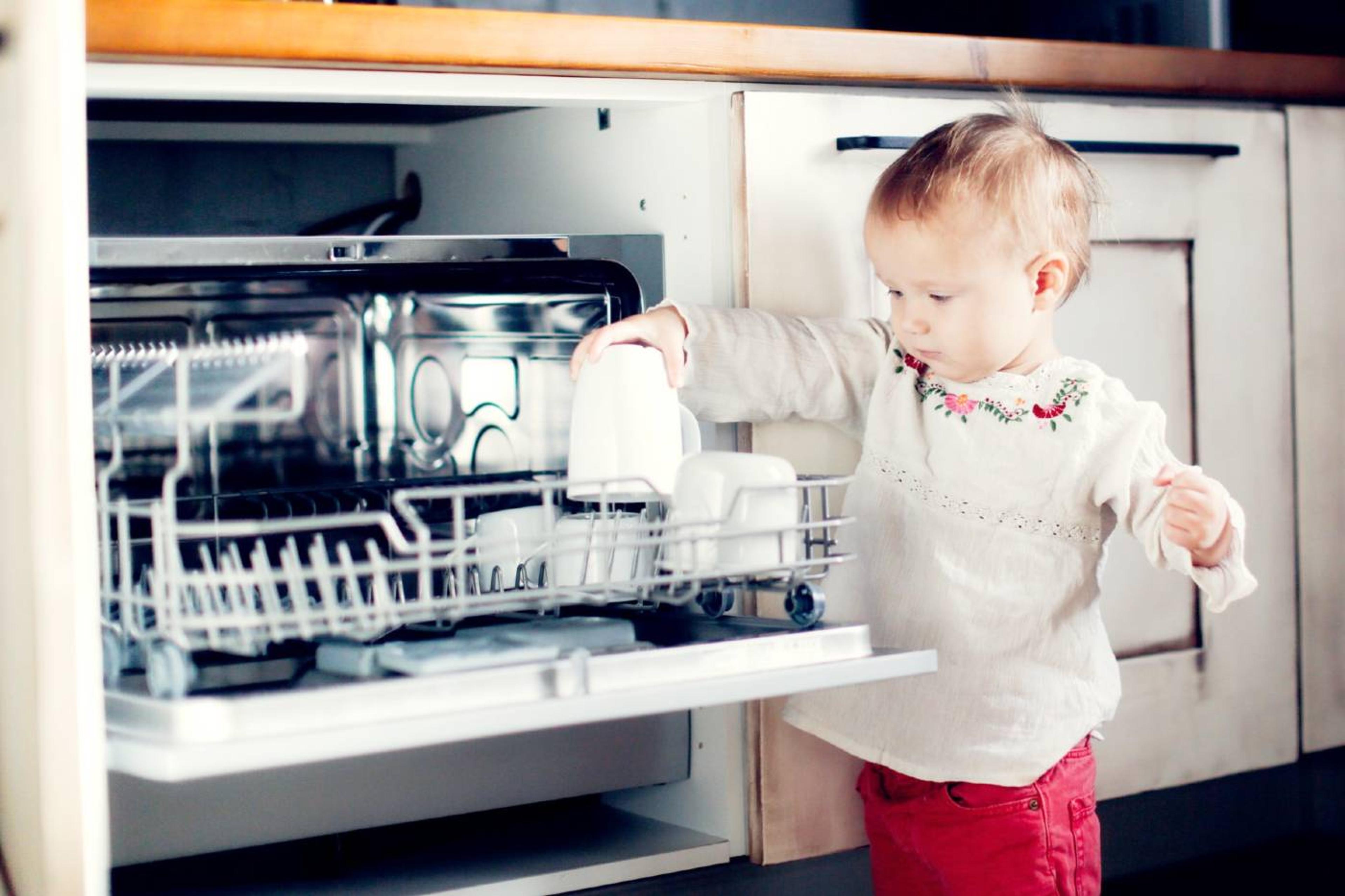 Young toddler helps unload the dishwasher.