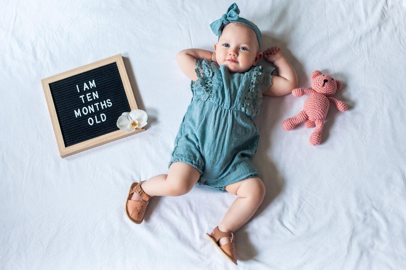 10-month-old baby girl posing next to letterboard