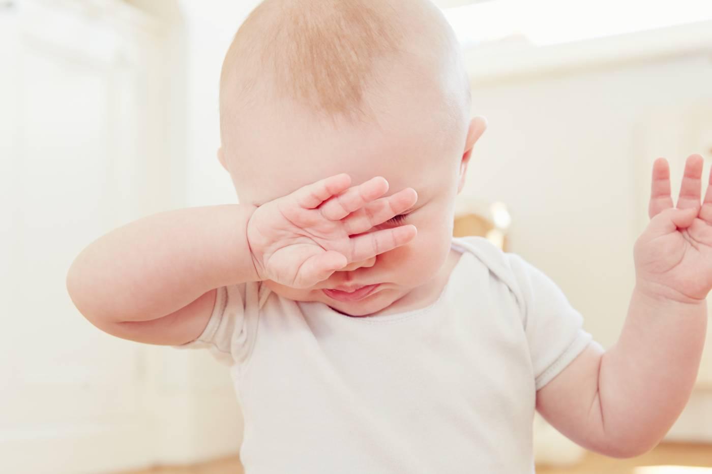Baby sleep mistakes: tired baby covering face