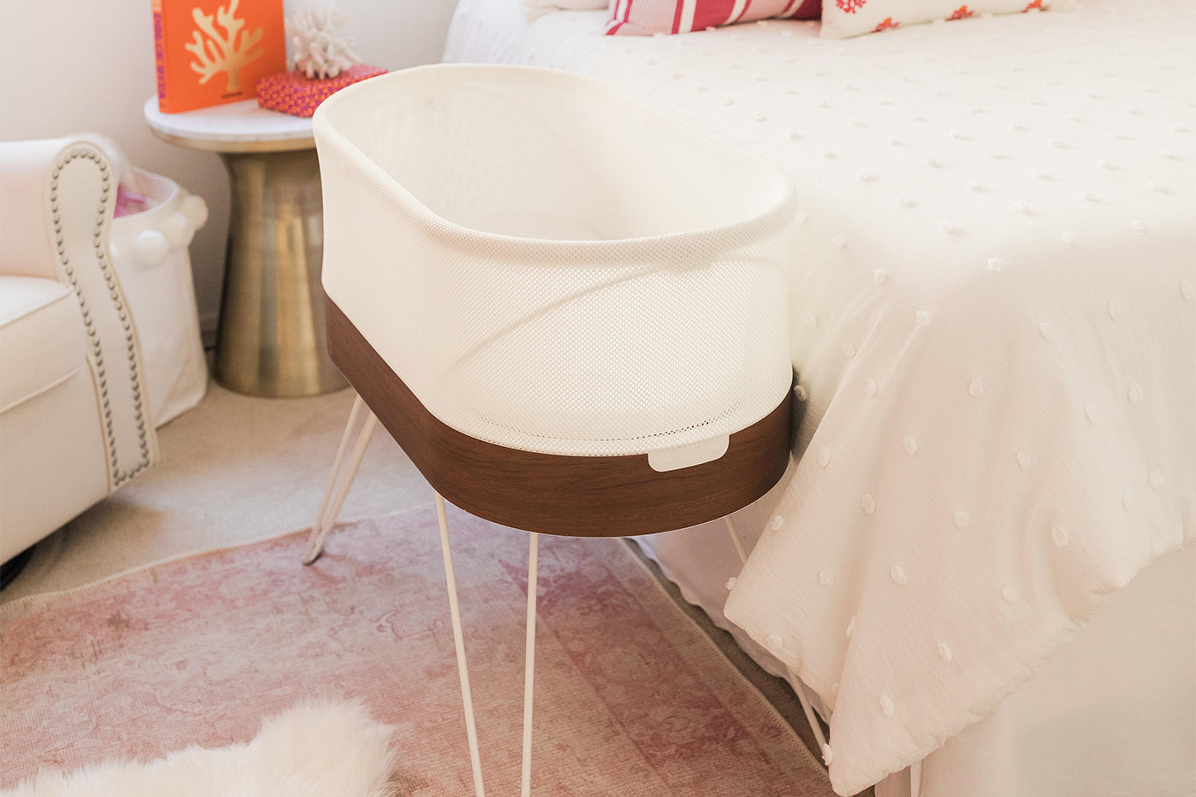 A SNOO Smart Sleeper bassinet next to a caregiver's bed