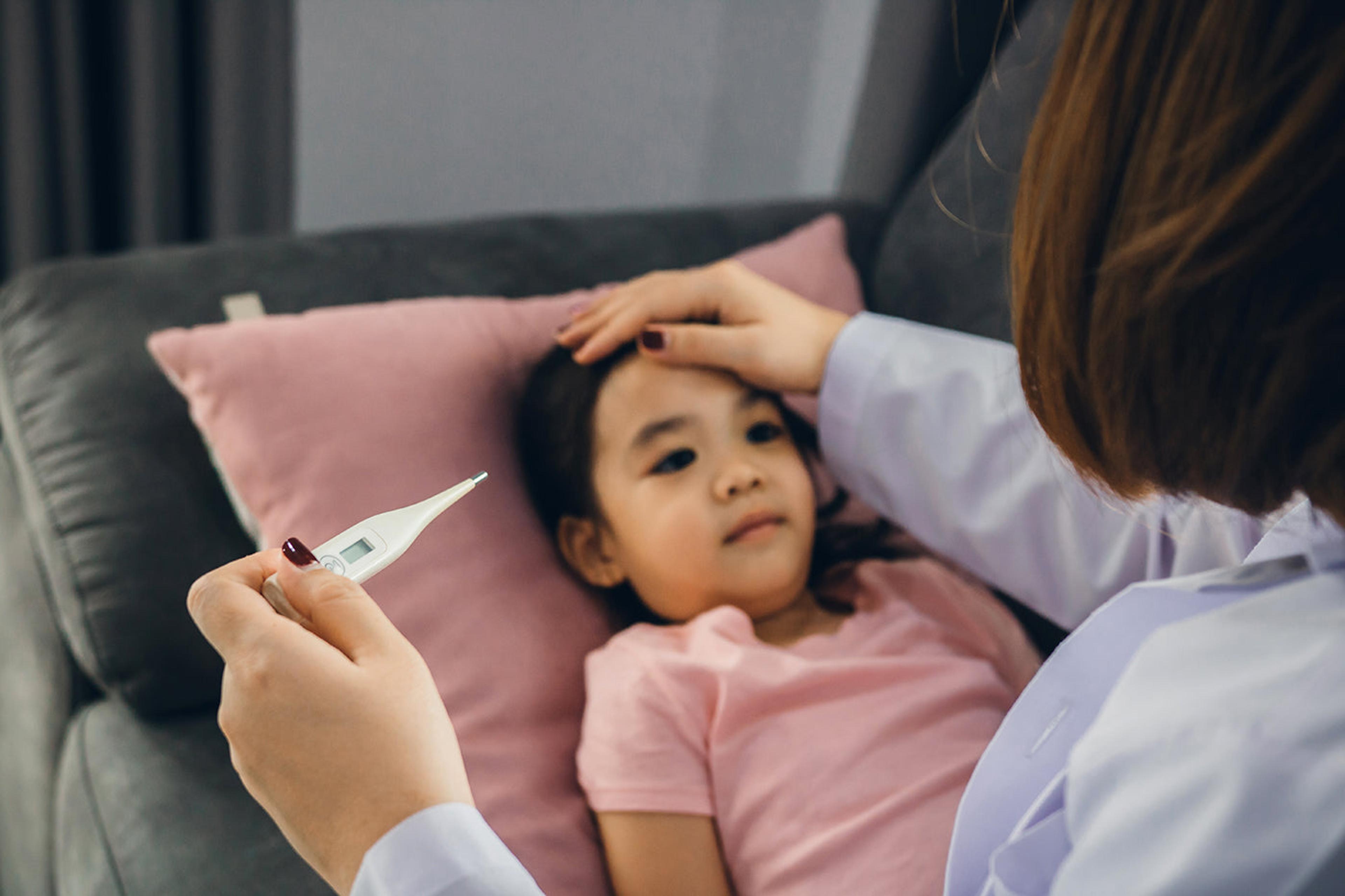 Cold, flu, or Covid? Child laying down, getting temperature taken.