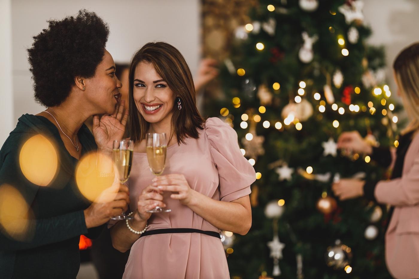 Two women share a secret at a holiday party