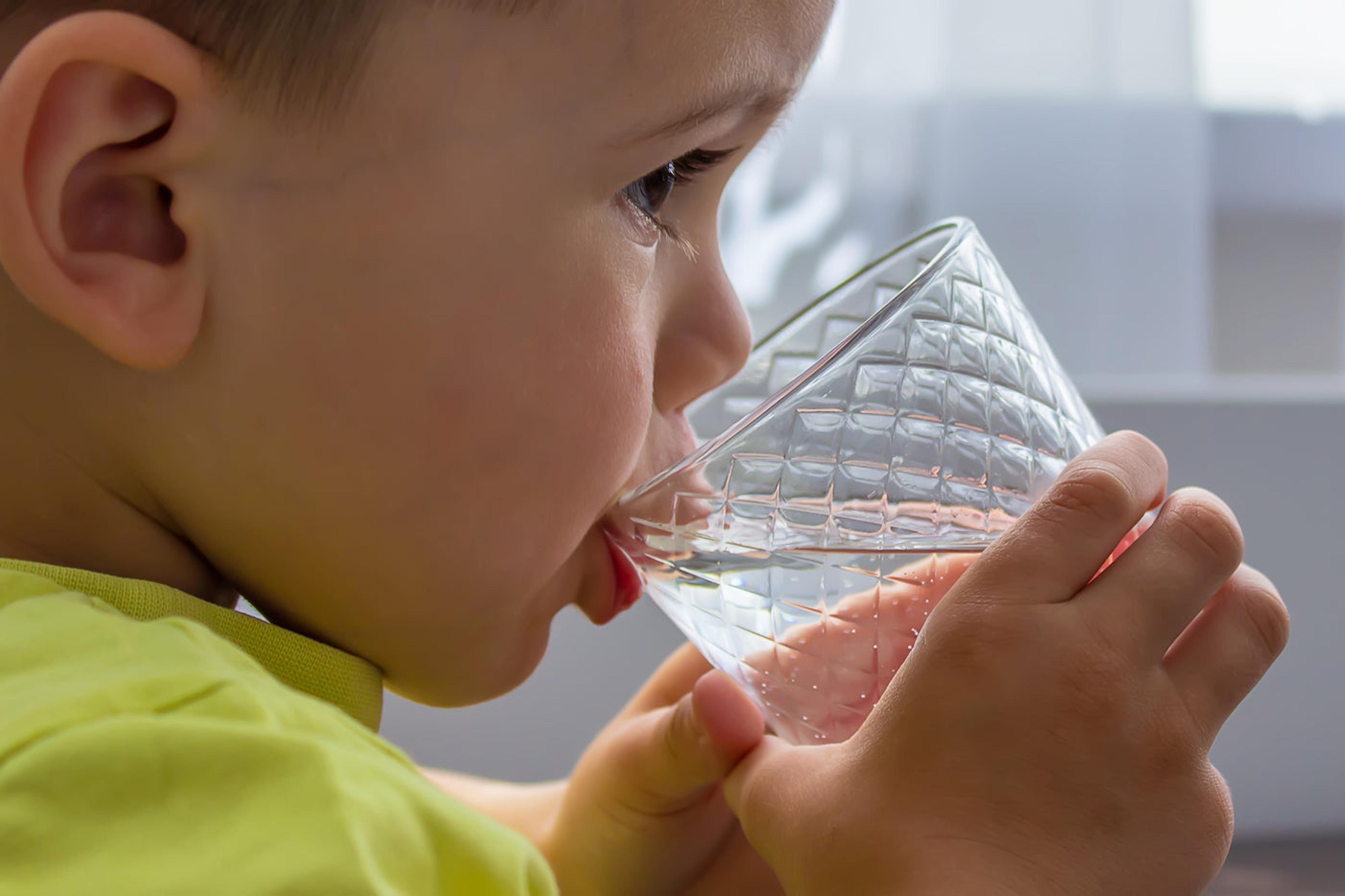 A toddler drinks a glass of water