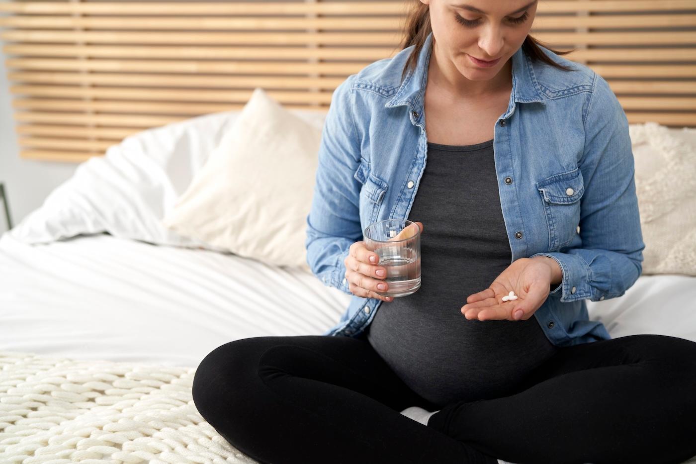A pregnan woman looks at melatonin pills in her hand