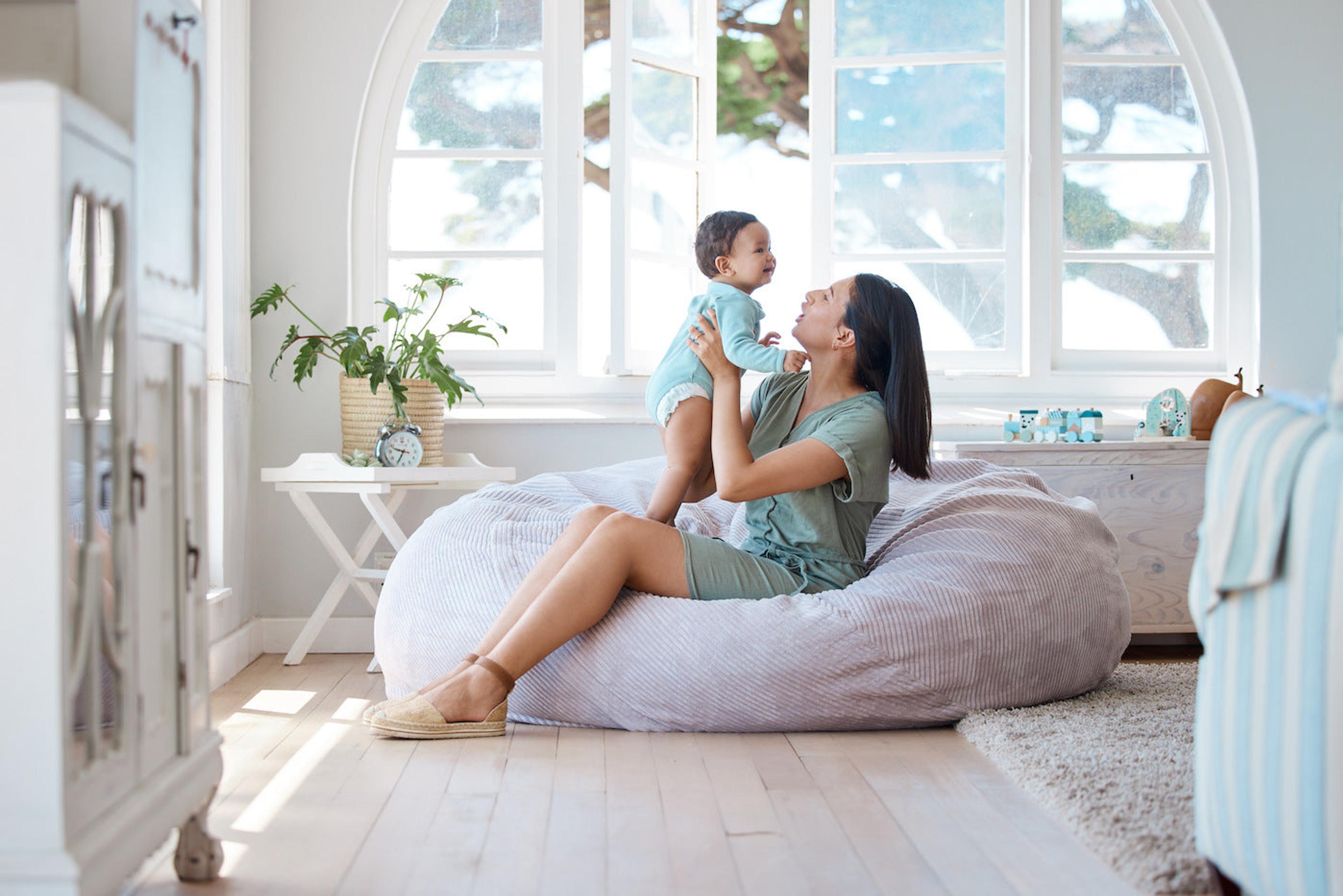A mother plays with her baby in a well-lit room