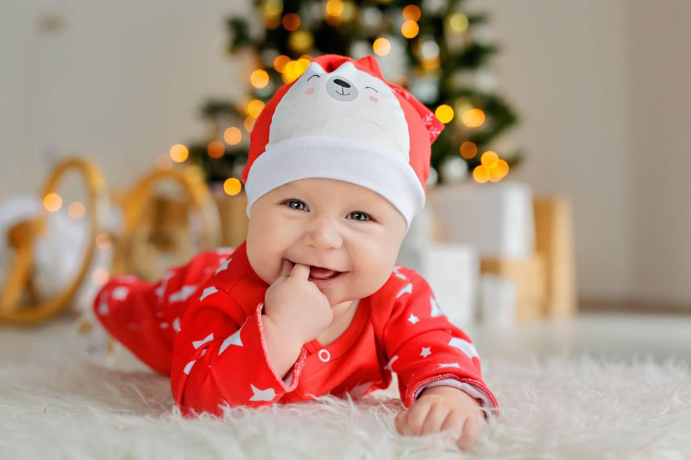 Smiling baby on tummy in front of Christmas tree