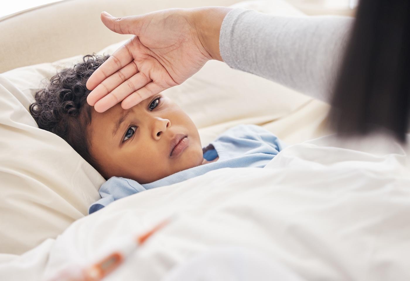 A mother checks her toddler son's forehead for a fever