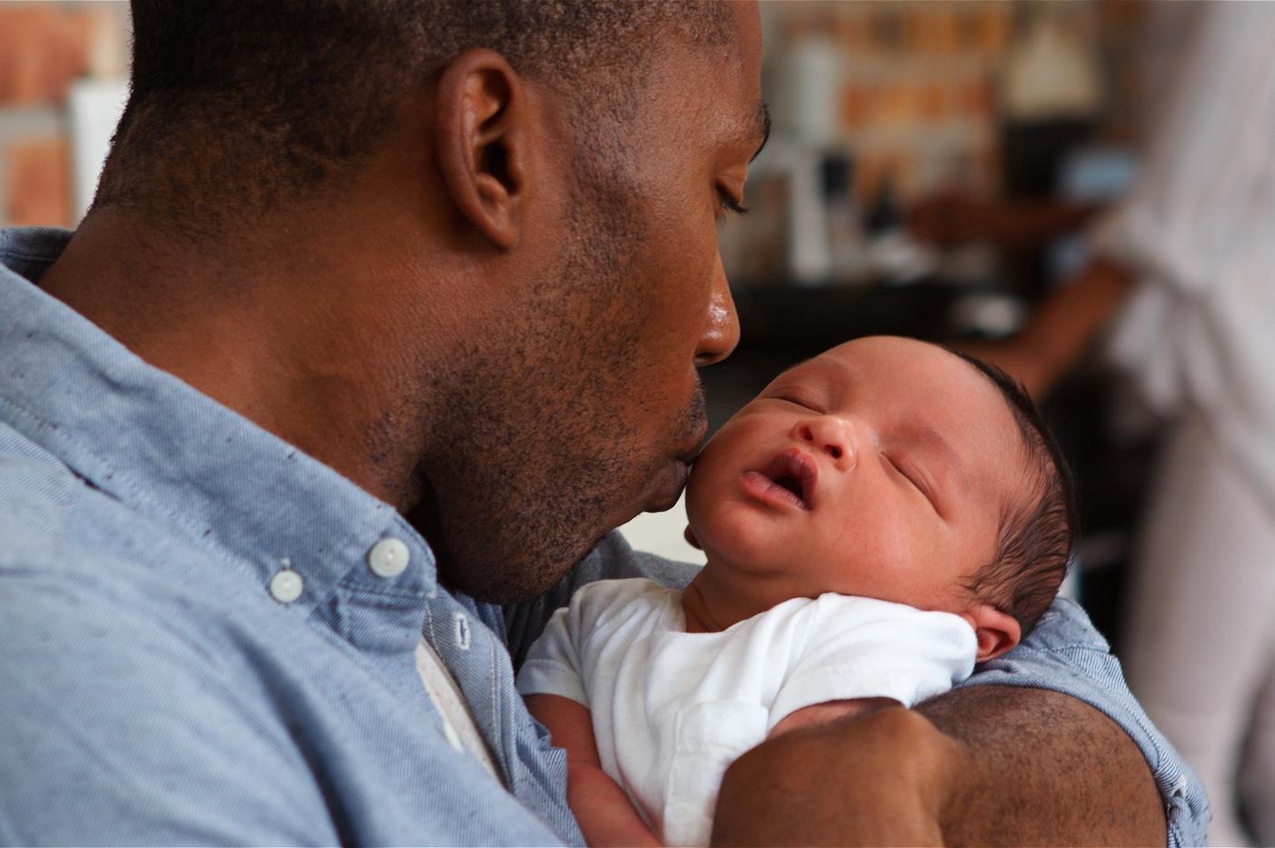 A new dad kisses his baby's cheek