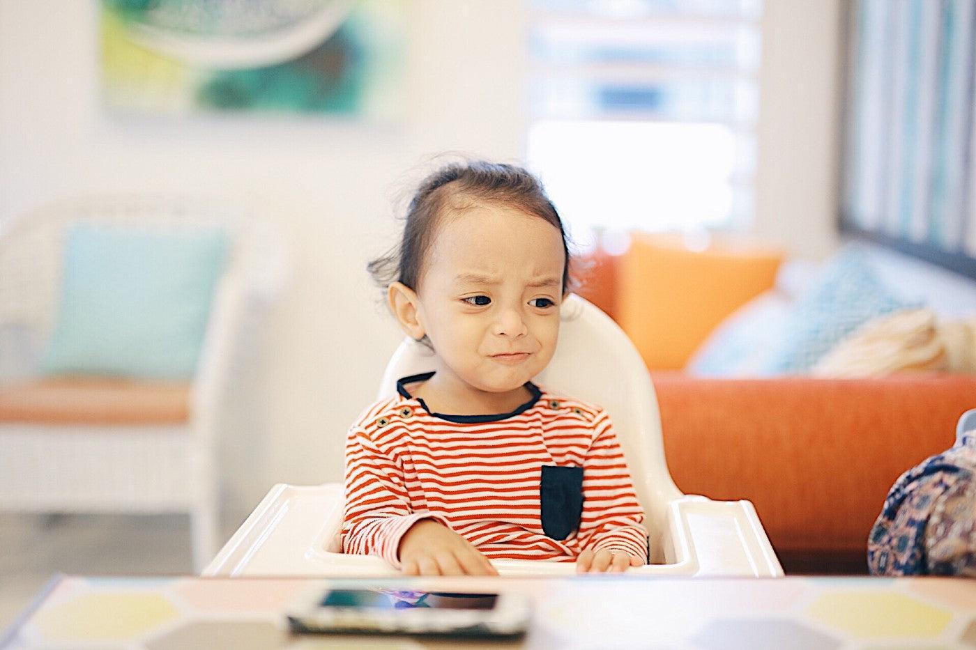 Toddler tantrum triggers: Unhappy toddler in highchair