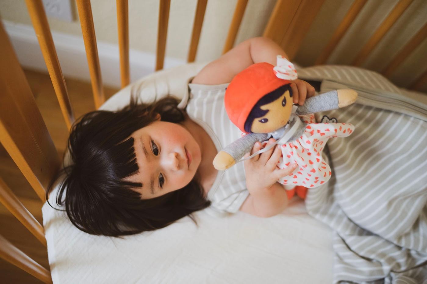 A toddler sleeps in a crib