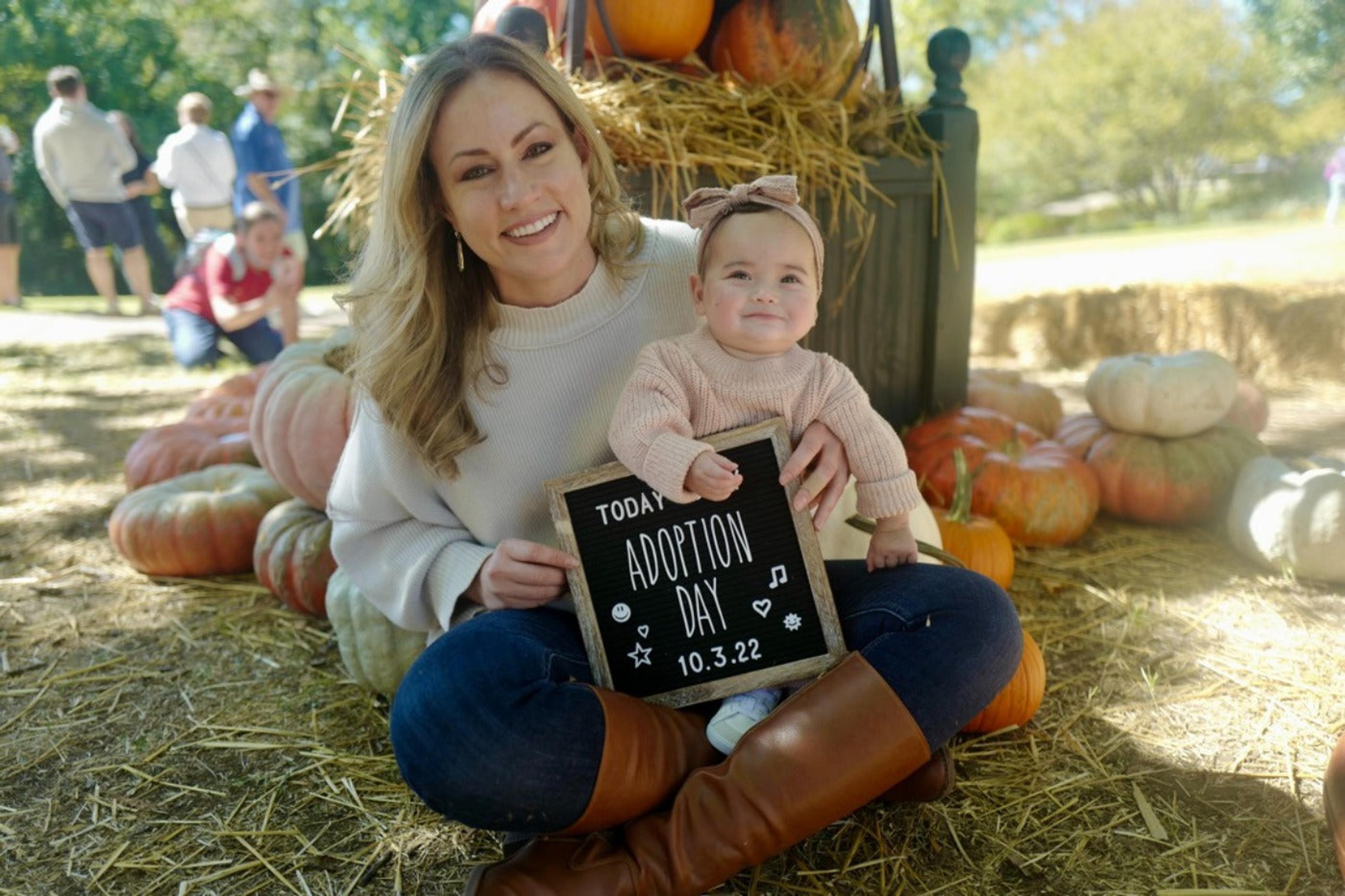 Laura Hutfless and daughter holding adoption day letter board