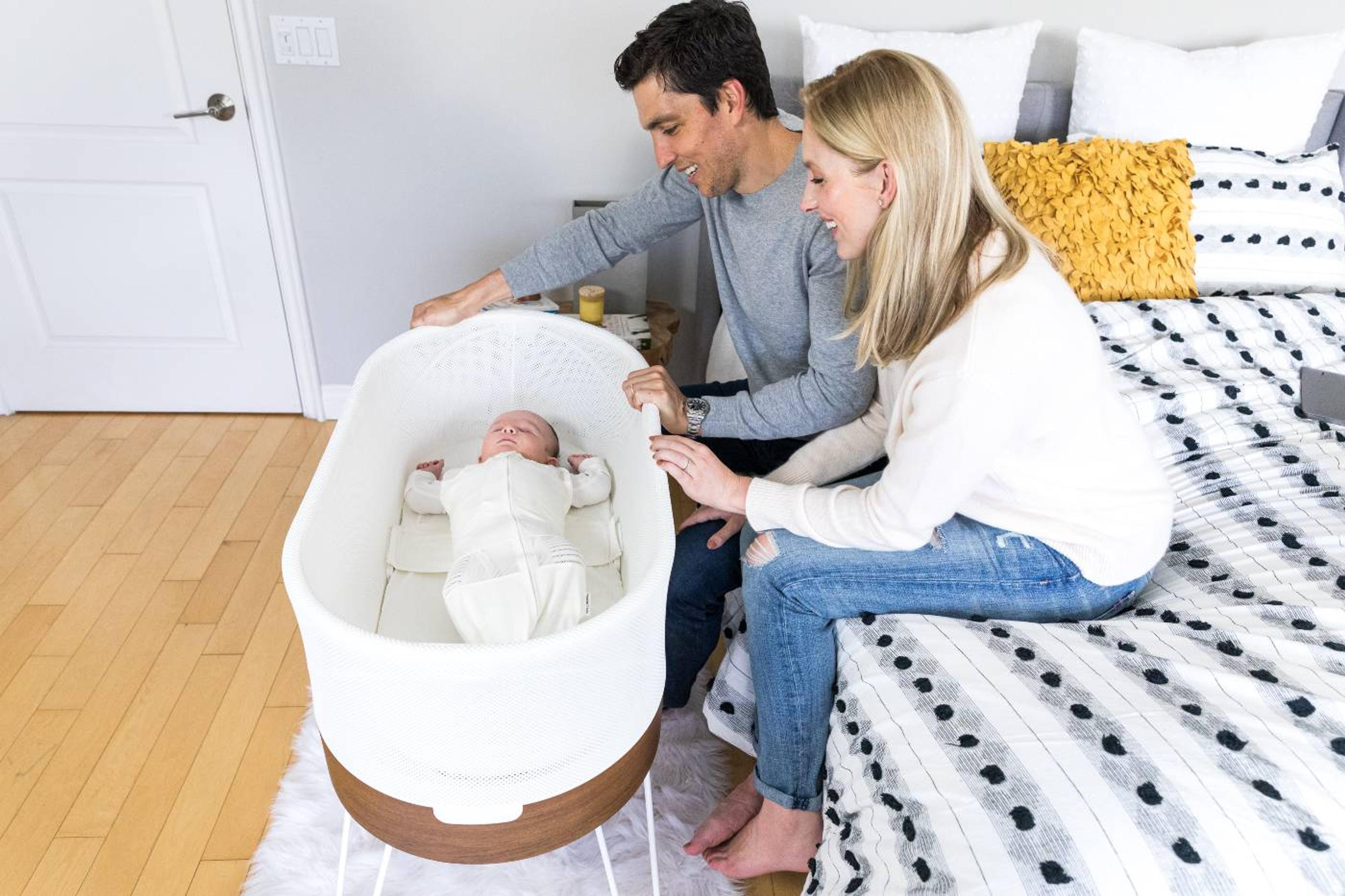 Baby sleeping in best rocking bassinet while parents look on
