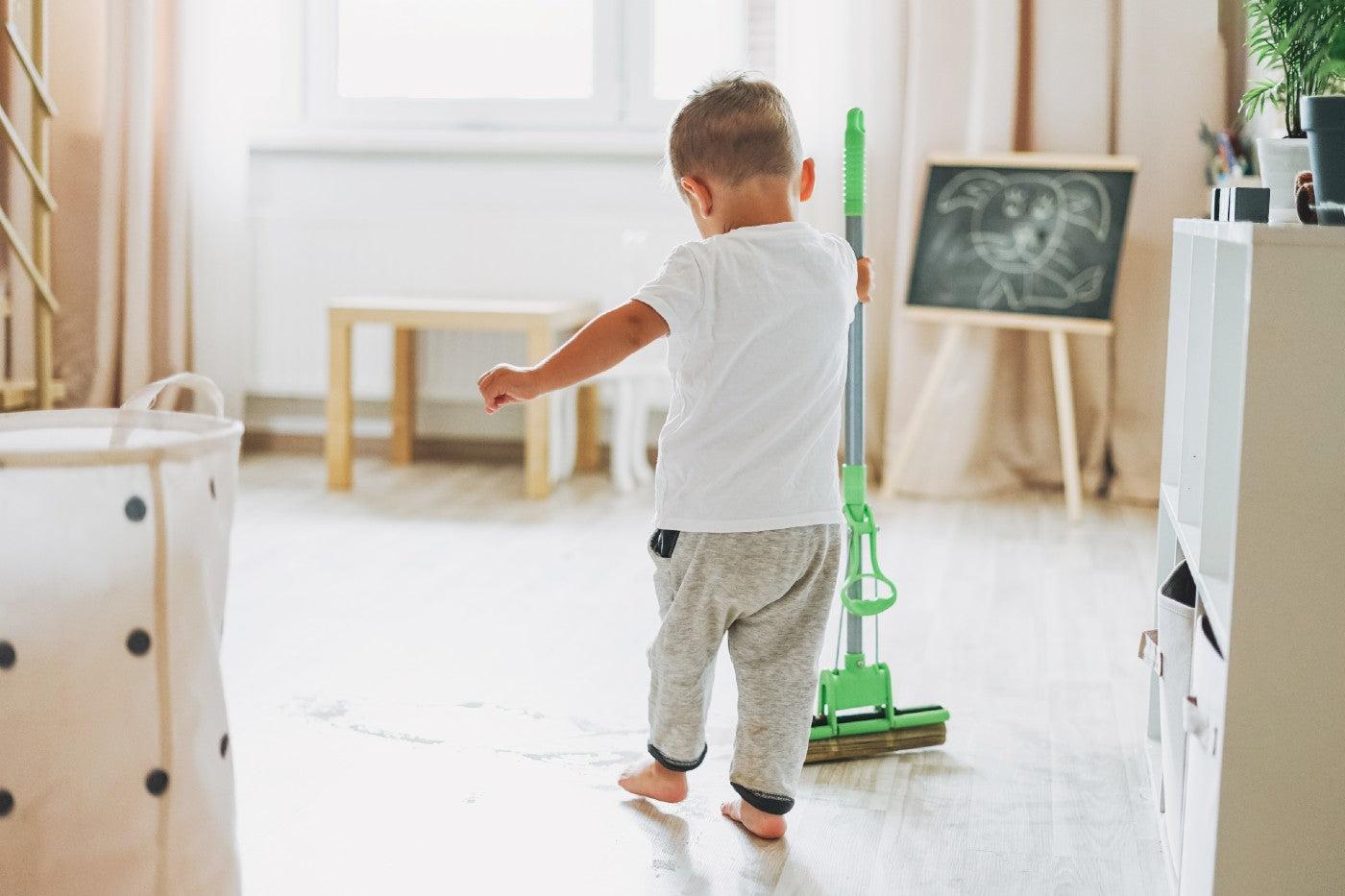 A little boy mops a children's room