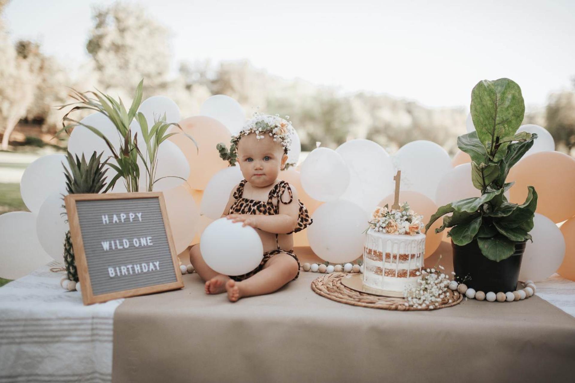 A baby celebrates her birthday at a "wild one" themed 1st birthday party