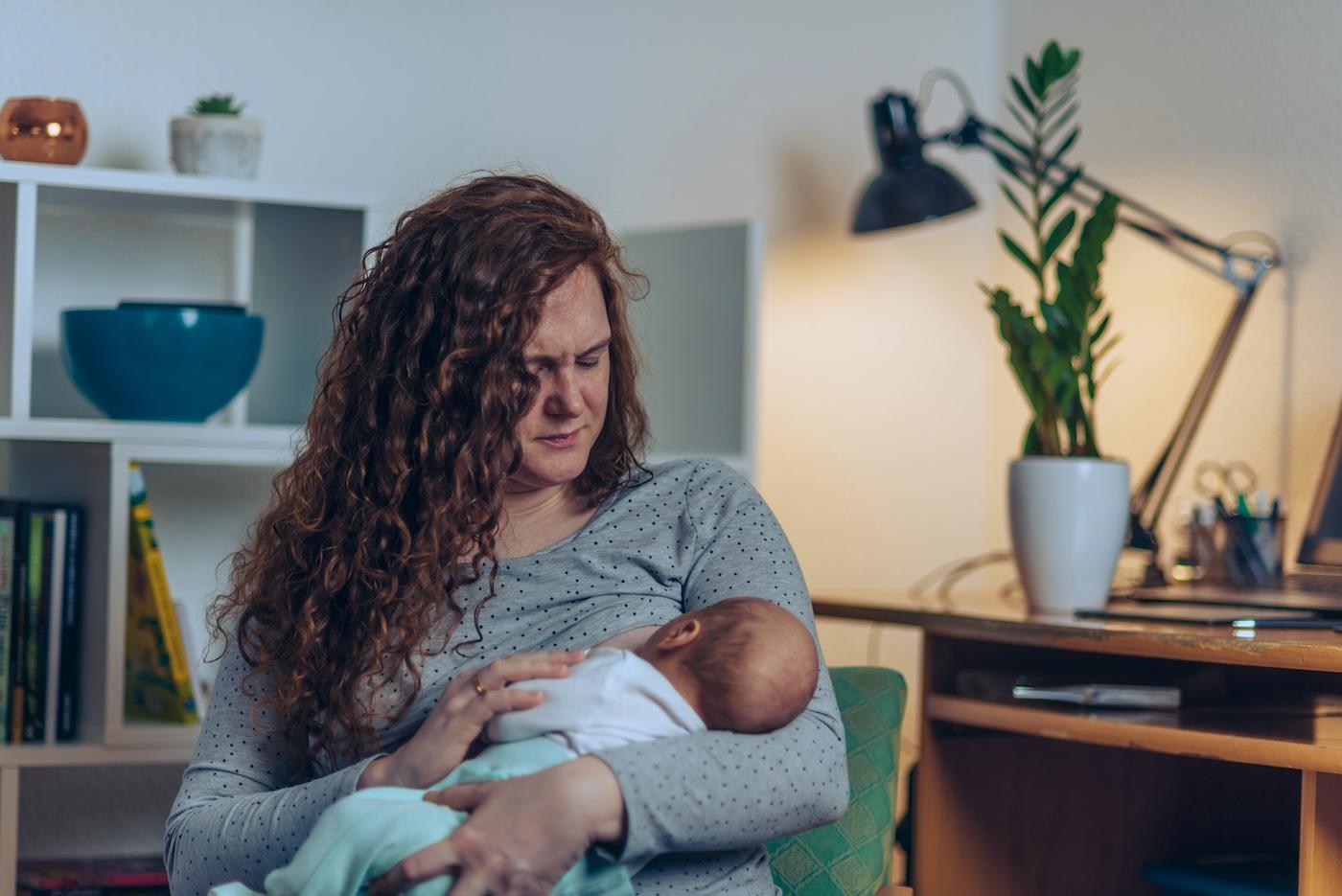 Mom making a pained face while breastfeeding