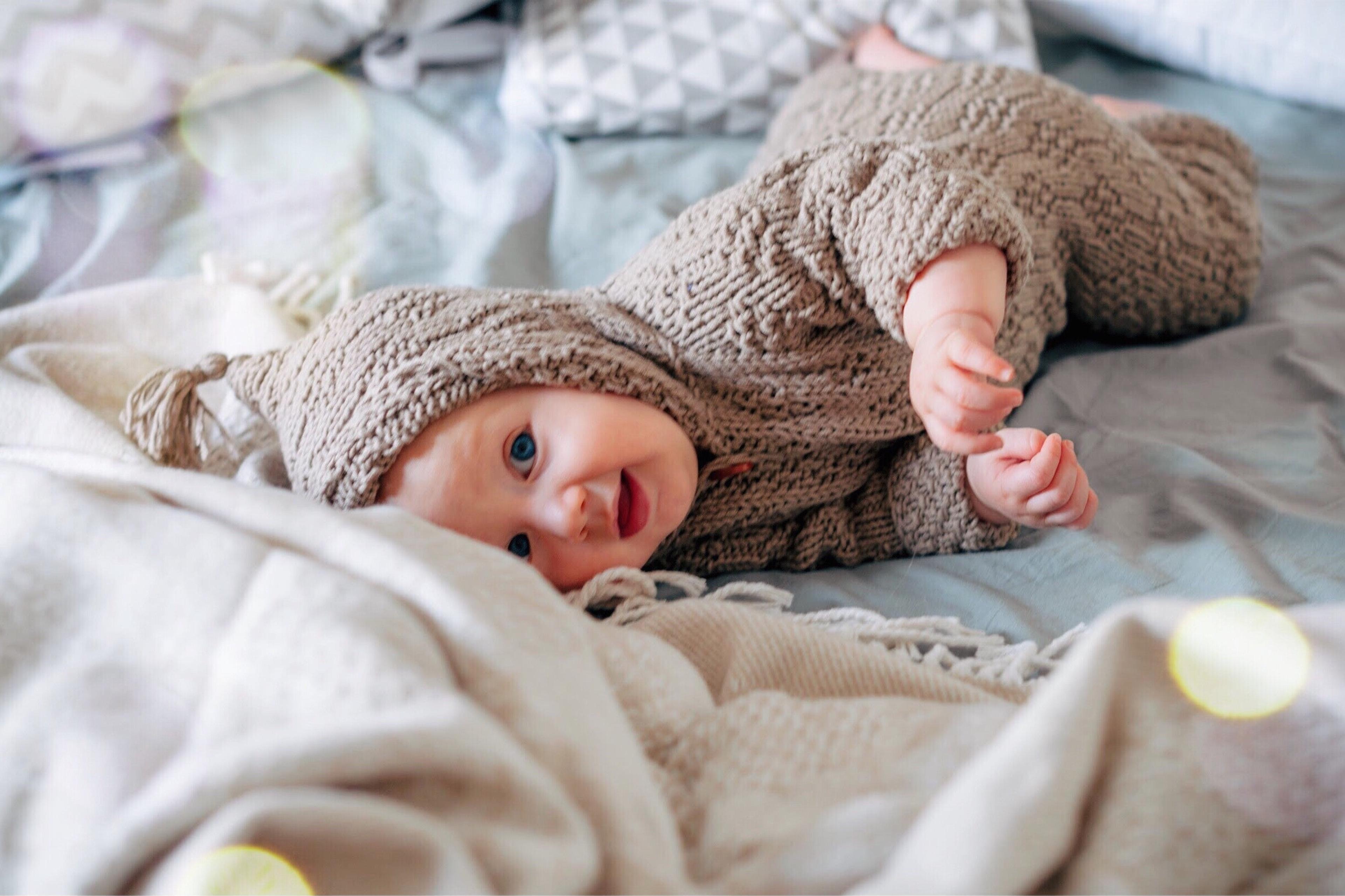 Norse baby names - baby wearing sweater laying on blankets