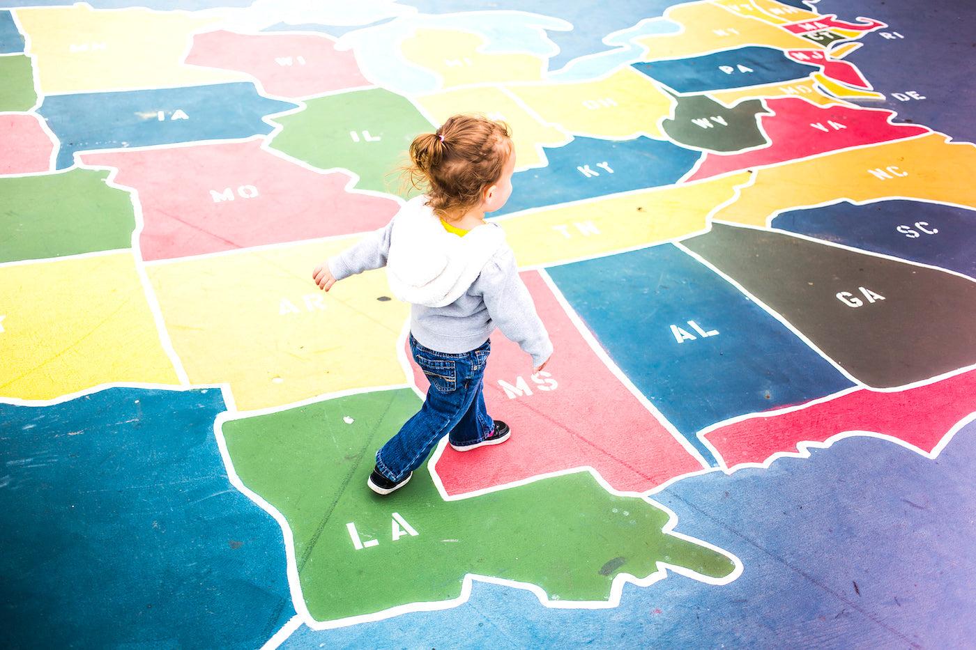 Toddler walking across a floor map of the United States