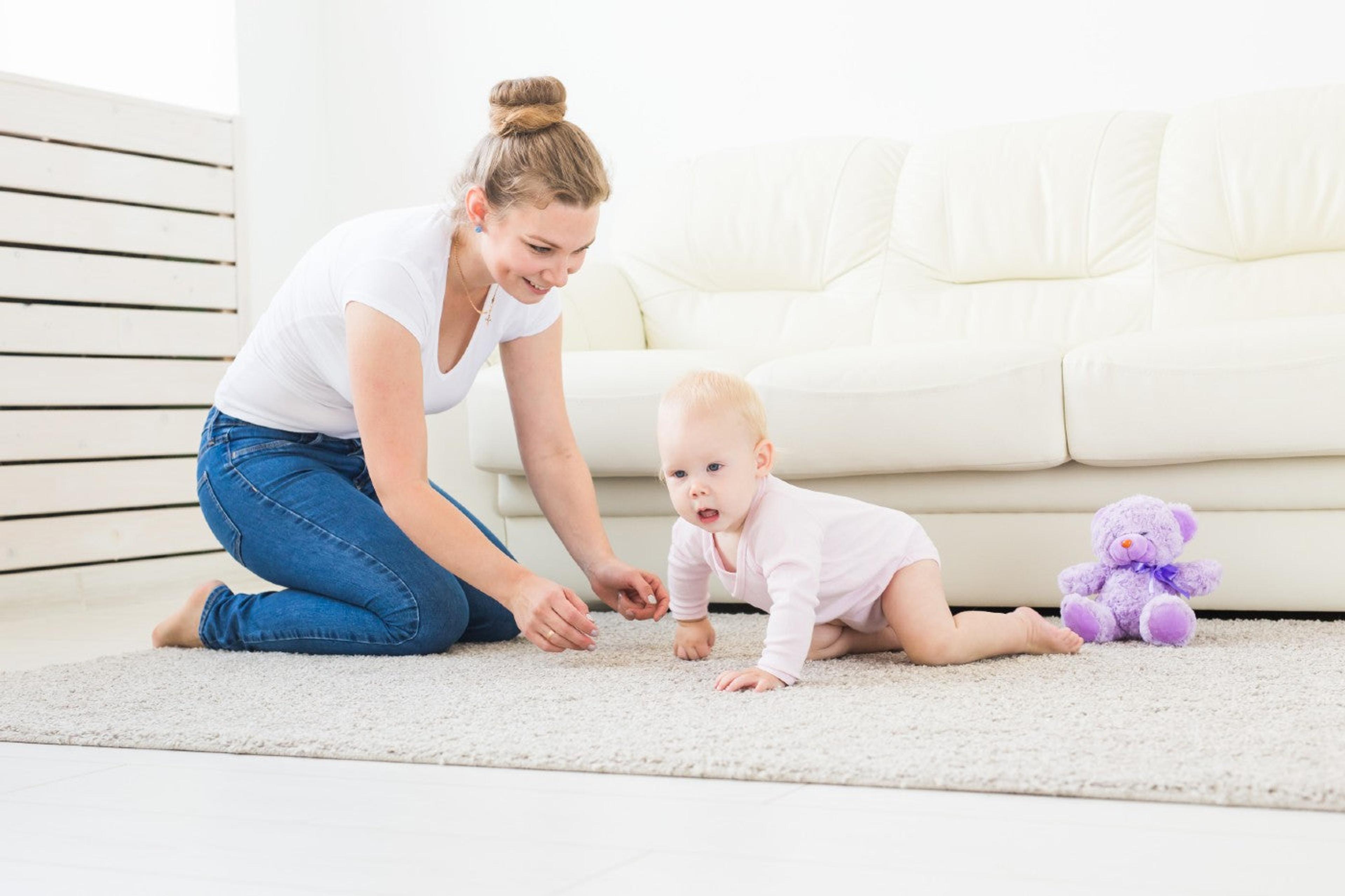 A mother helps her newly crawling baby