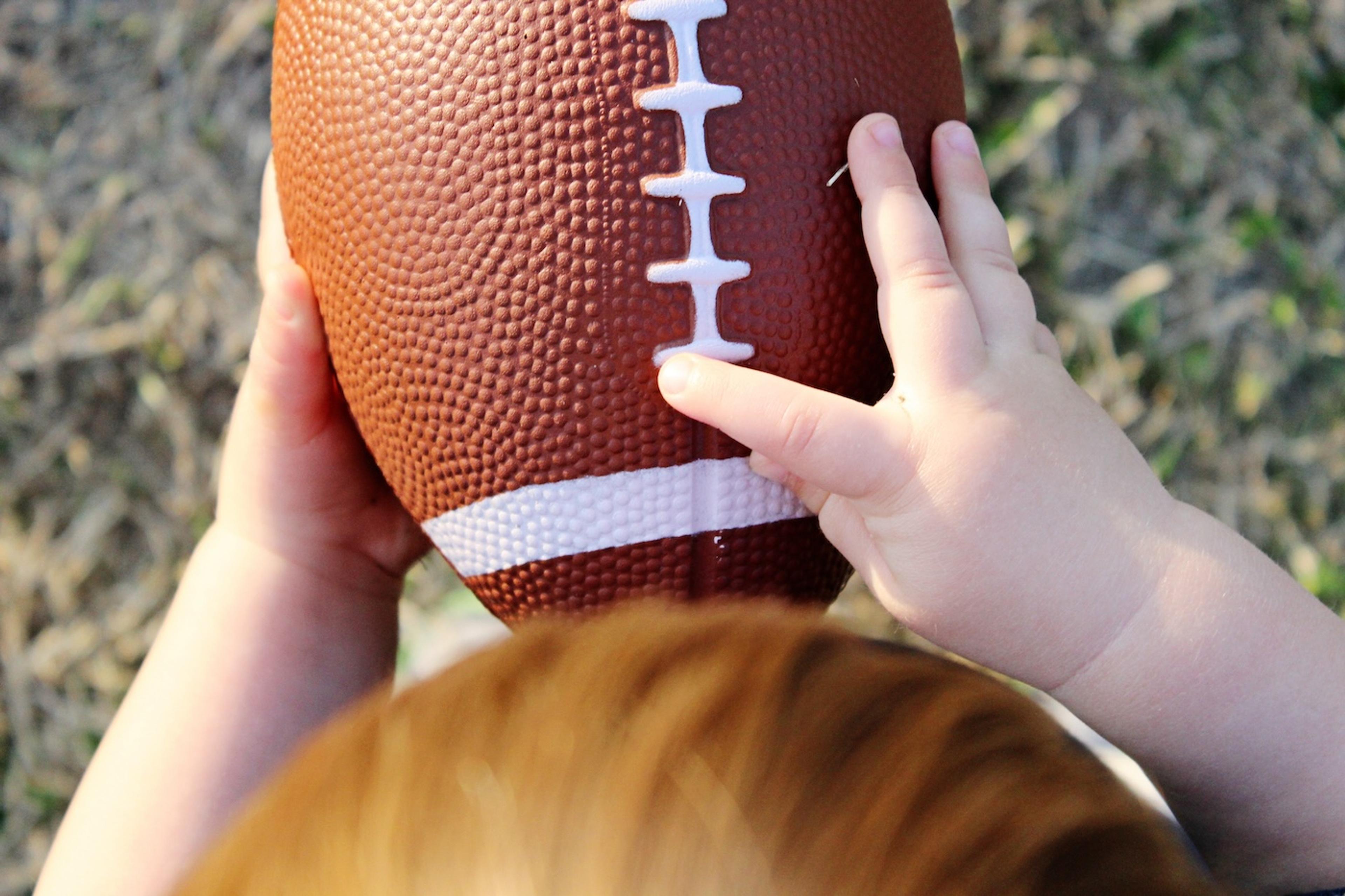 A toddler holds a football