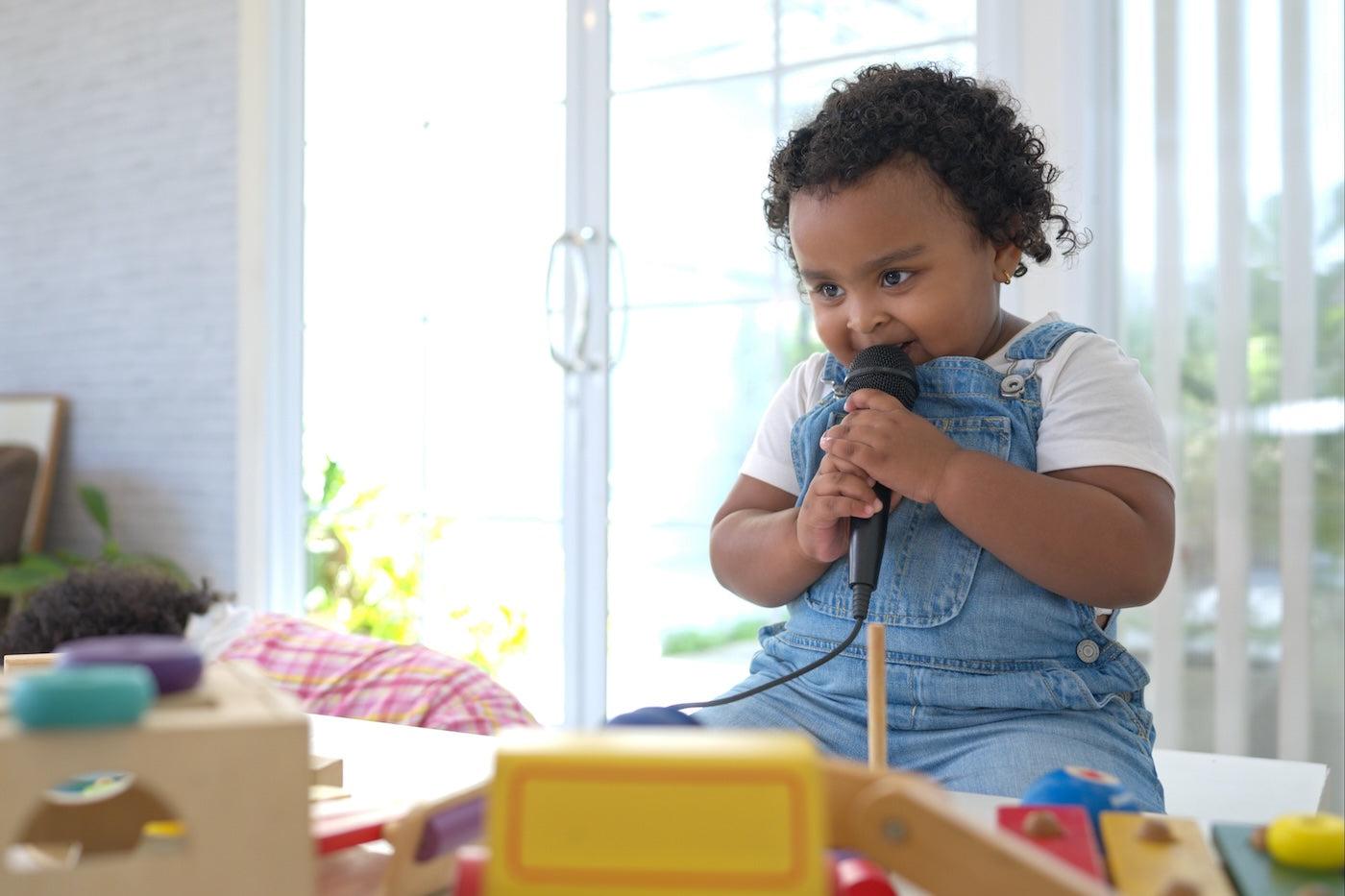 2-year-old girl talks into a toy microphone