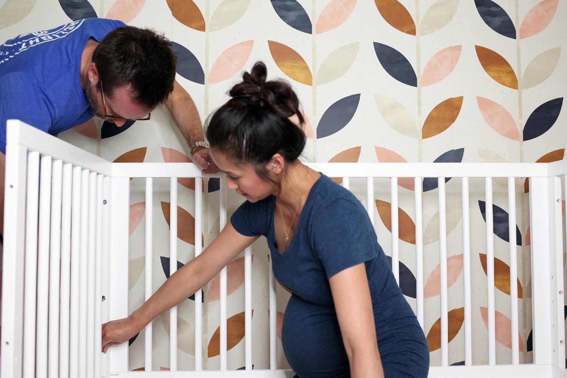 Man and pregnant woman complete a DIY nursery project