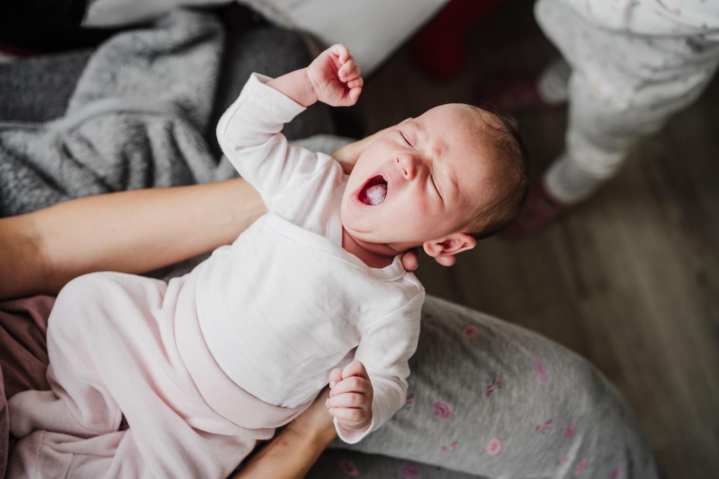 A newborn yawns in their parent's arms