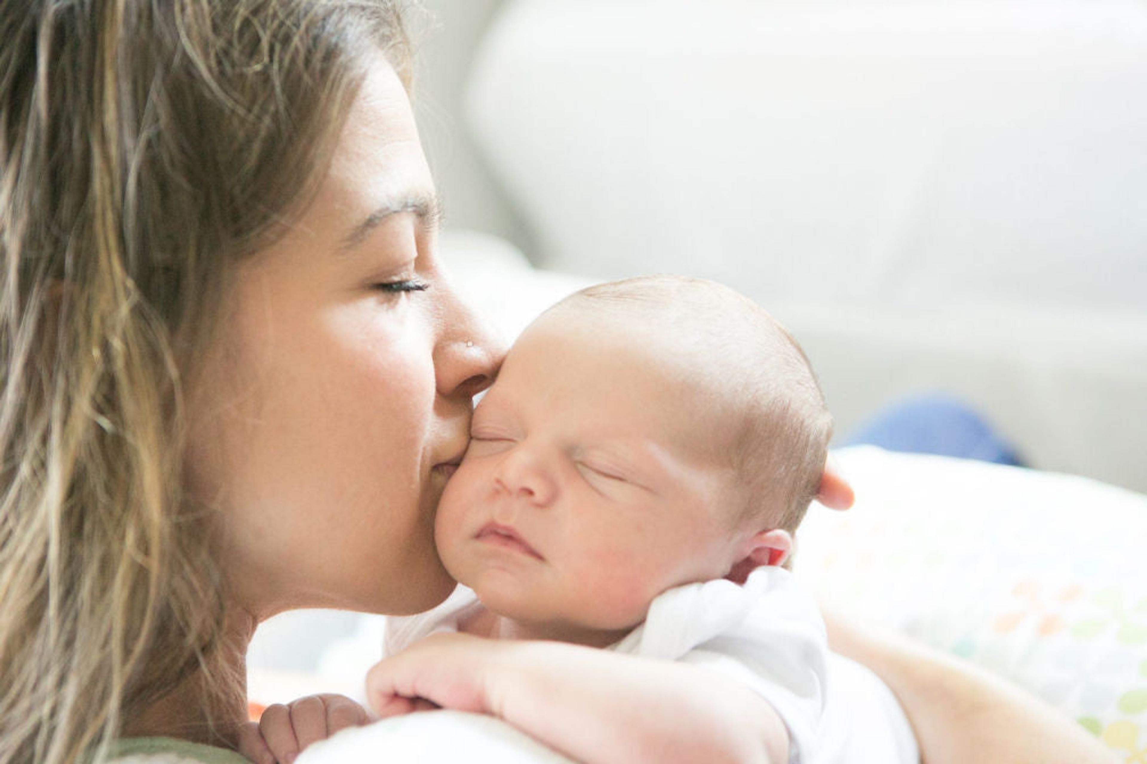 A mom kisses her baby's head at bedtime